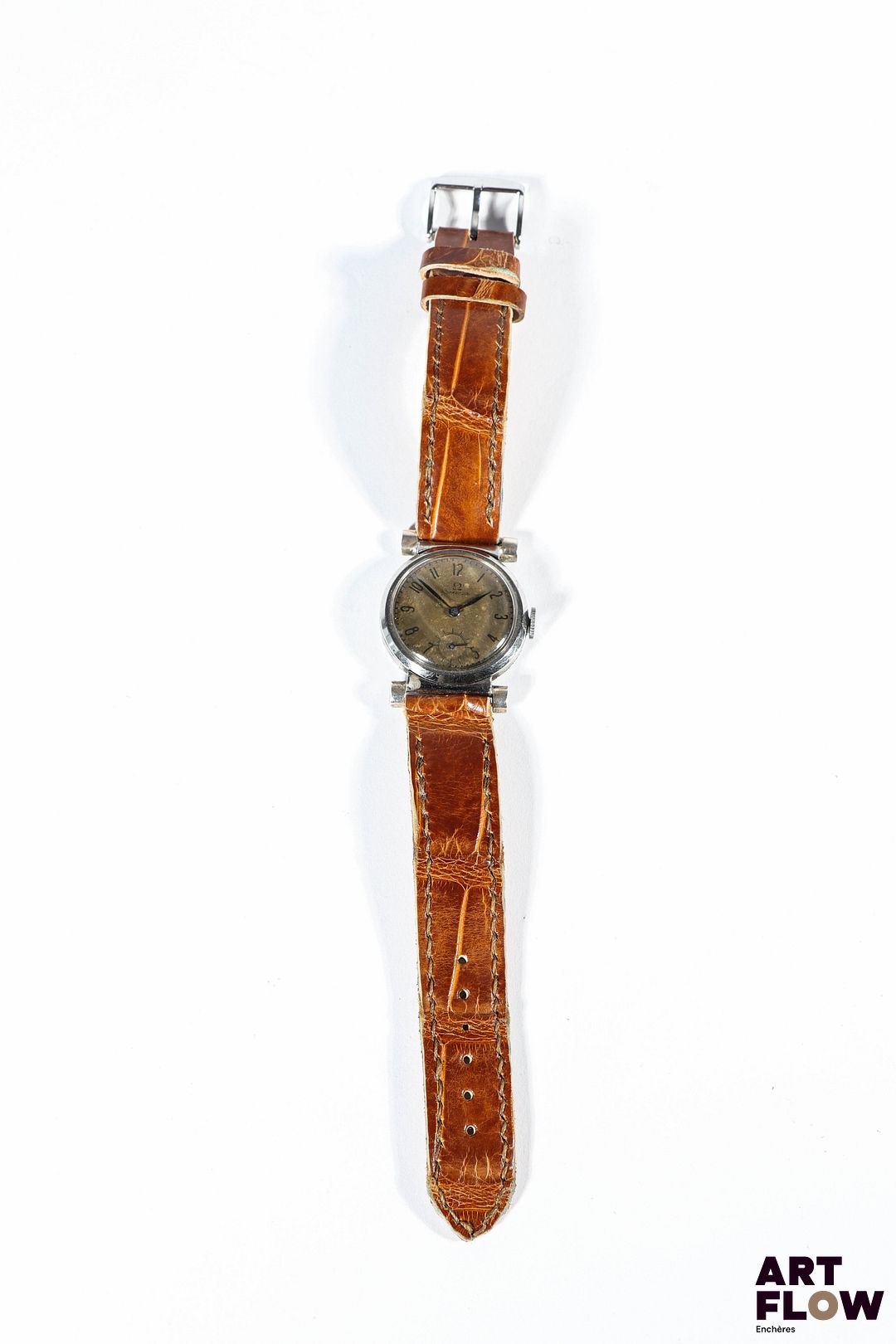 OMEGA Montre bracelet homme en acier, modèle Scarab, à mouvement mécanique à remontage manuel, le boîtier rond à cadran à fond patiné, index en chiffres arabes, aiguilles bleuies, lunette lisse, le bracelet en cuir d'alligator brun. Années circa 1930 Diamètre 30mm Longueur du bracelet : 18 cm env. Fondée en 1848, Omega a su produire des montres au design original, représentatives du mouvement Art déco. Cette Omega Scarab en fait partie, notamment grâce à ses cornes caractéristiques de cette période. Bon état général (cadran patiné) Fonctionnelle au moment de la rédaction du catalogue, mécanisme non garanti.
