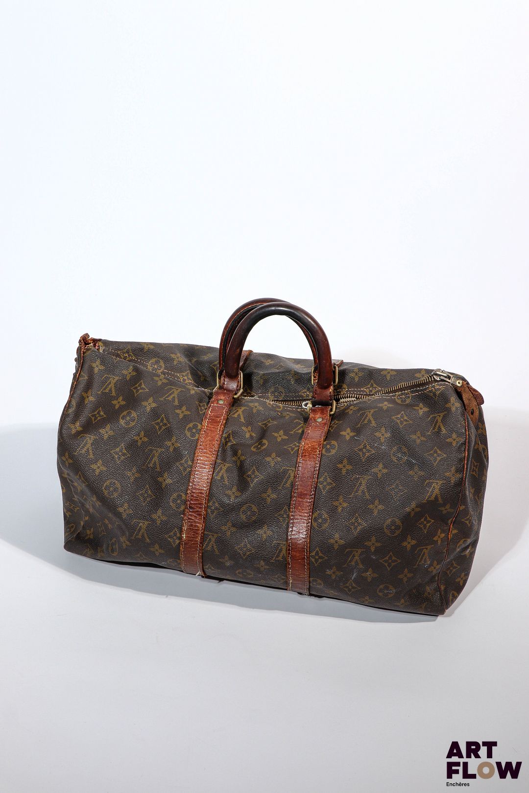 LOUIS VUITTON Modèle Keepall Sac vintage en toile enduite monogrammée et cuir Dimensions : 31 x 50 cm Taches, coutures effilochées, griffures, trou, cuir craquelé