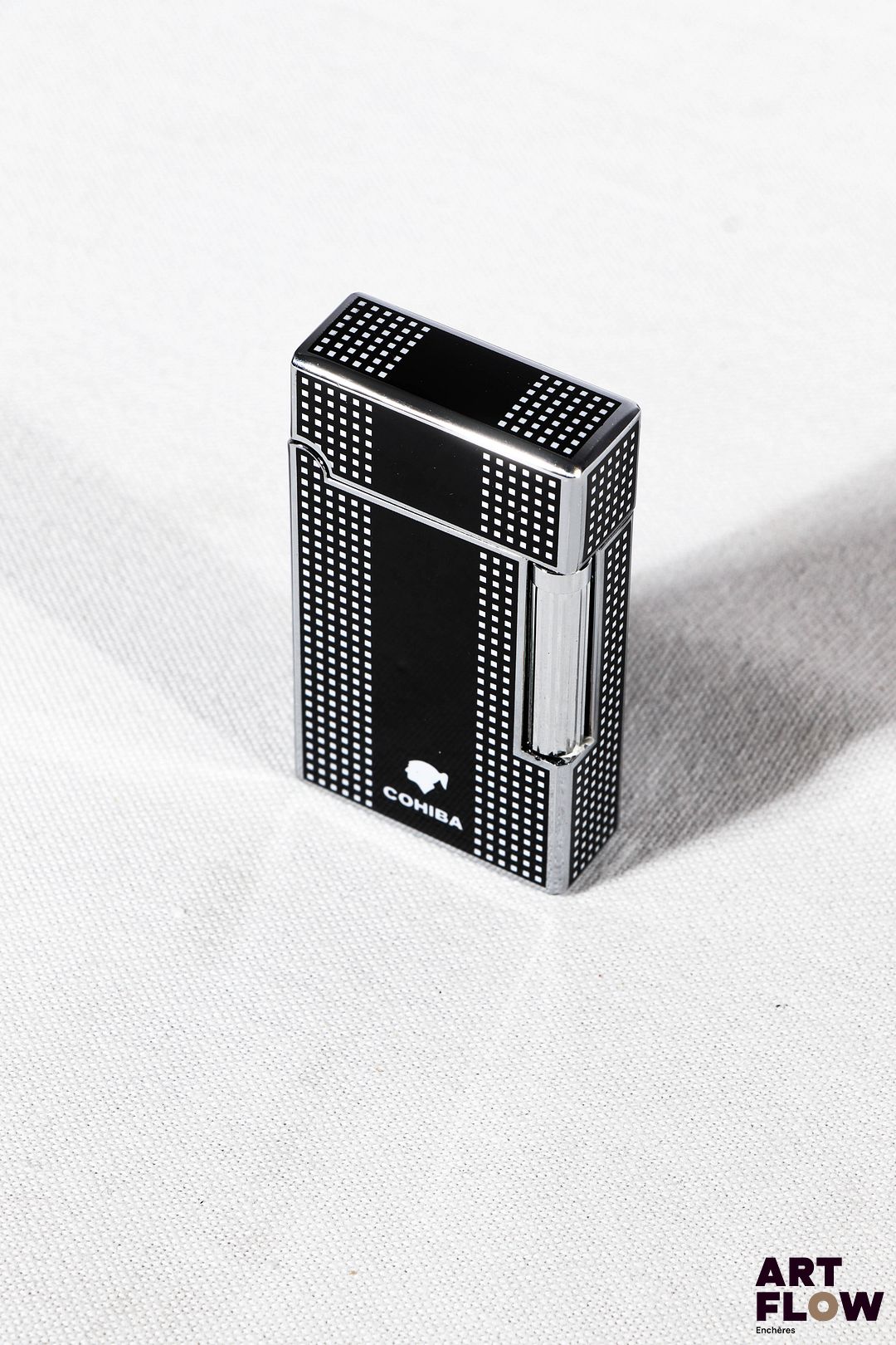 COHIBA Briquet en métal argenté laqué à décor géométrique noir et blanc. Partie base du briquet de couleur orange 6,5 x 3,5 cm Dans son écrin Très bon état général