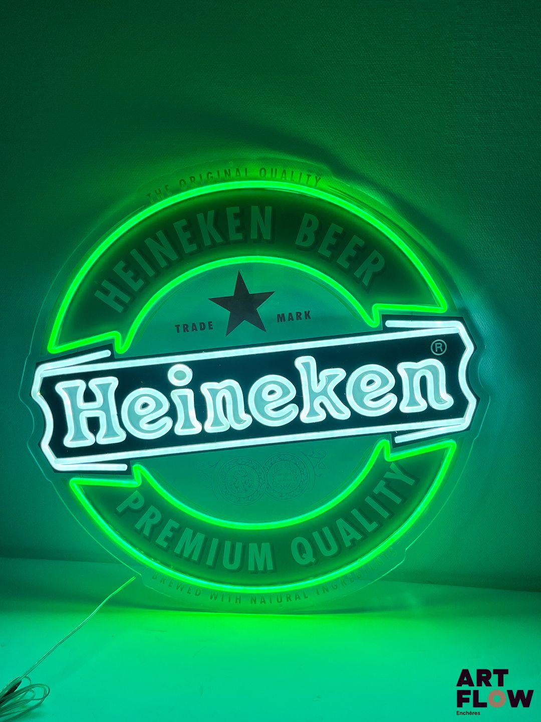 Enseigne lumineuse publicitaire sur plexiglas Heineken. Diamètre : 60 cm Fonctionnelle - État général excellent. Fourni avec son alimentation murale.