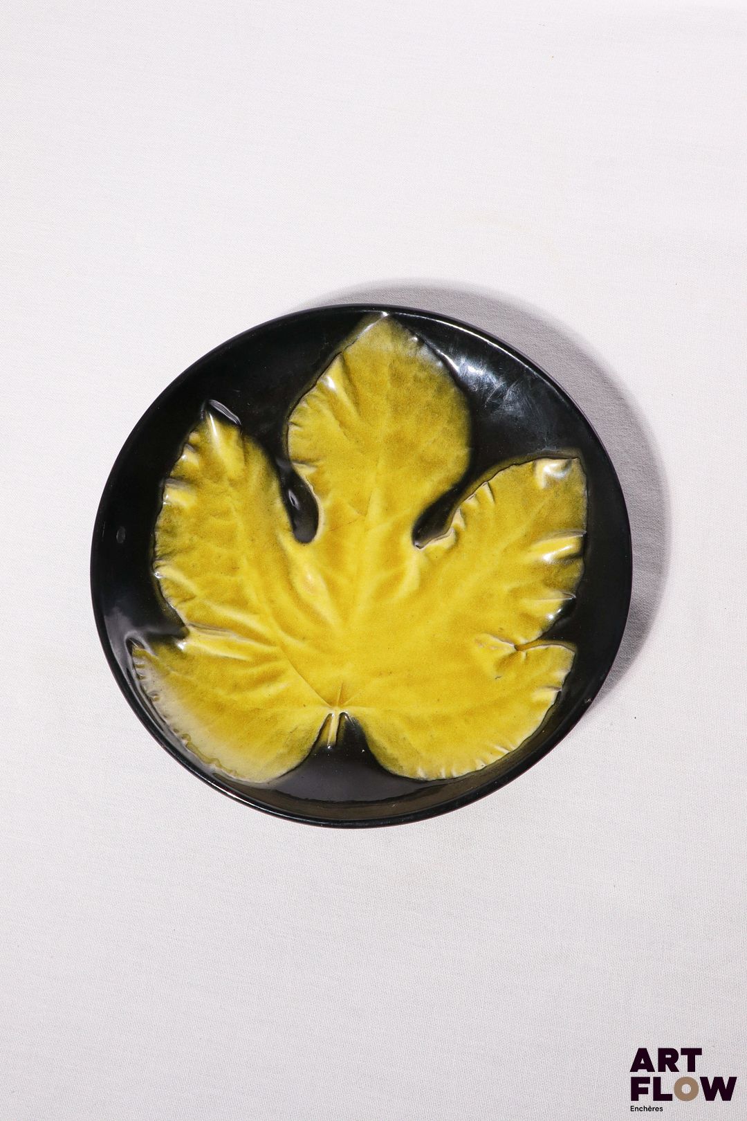 POL CHAMBOST (1906-1983) Assiette 864 "Feuille" en faience émaillée à couverte noire et jaune Tampon "Made in France" Diam. 23 cm Bibliographie : Philippe Chambost, "Pol Chambost, Sculpteur-Céramiste 1906-1983", Somogy Editions d'Art, Paris, 2006, modèle similaire p. 76