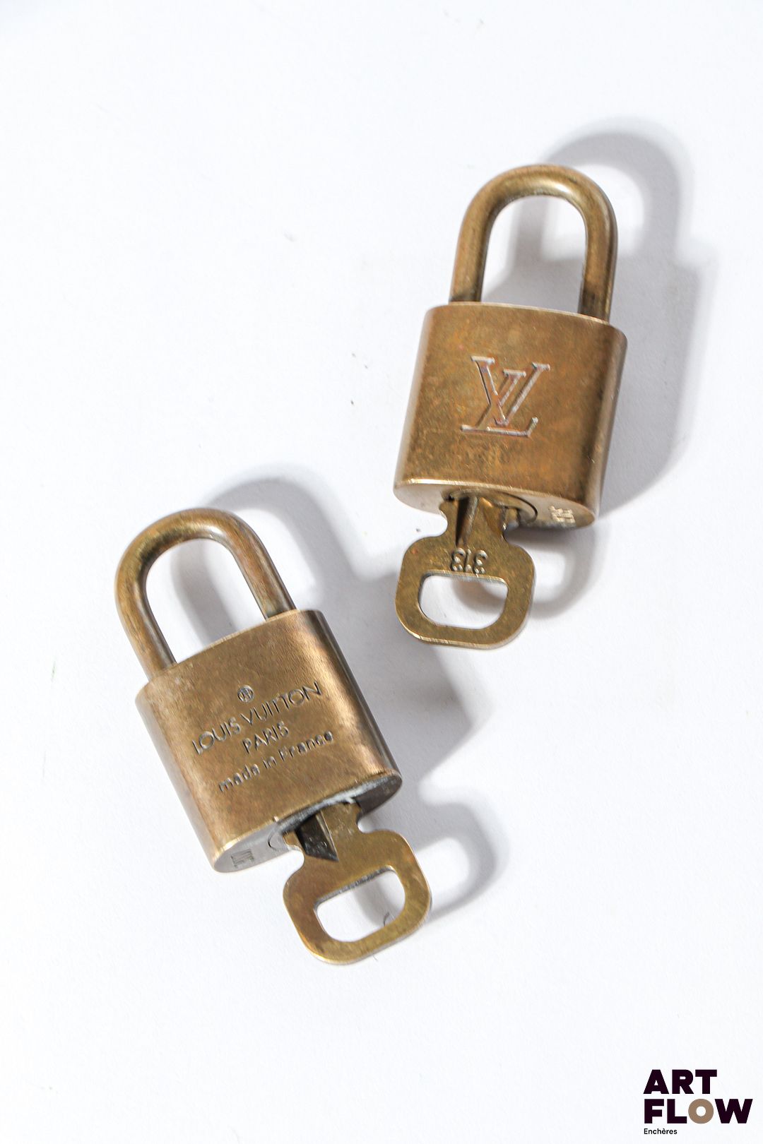 LOUIS VUITTON Ensemble de deux cadenas en métal doré monogrammés Dimensions : 4 cm