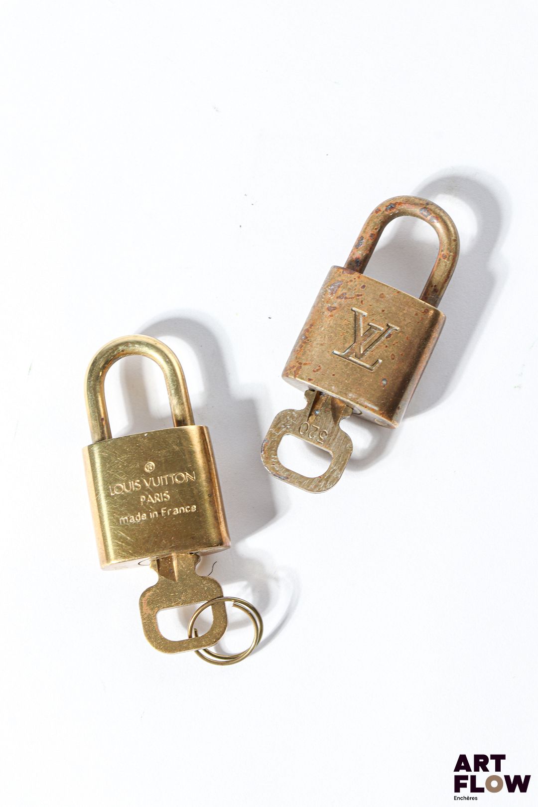 LOUIS VUITTON Ensemble de deux cadenas en métal doré monogrammés Hauteur : 4 cm