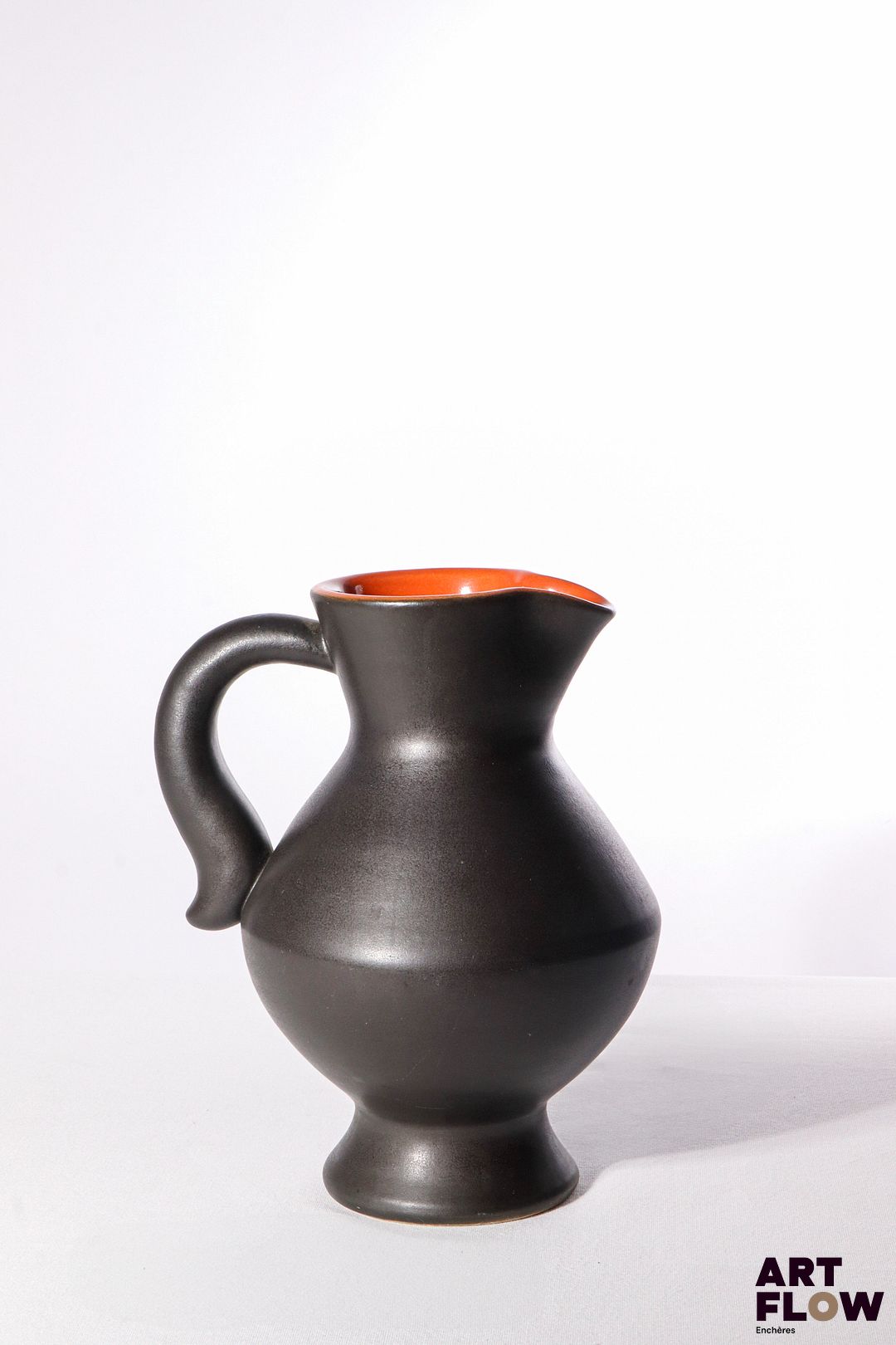 POL CHAMBOST (1906-1983) Pichet 835 en faience émaillée à couverte noire à l'extérieur et orange à l'intérieur. Incisé sous la base "835, Made in France, Poterie Pol Chambost" H. 24 cm Bibliographie : Philippe Chambost, "Pol Chambost, Sculpteur-Céramiste 1906-1983", Somogy Editions d'Art, Paris, 2006, modèle similaire p. 55