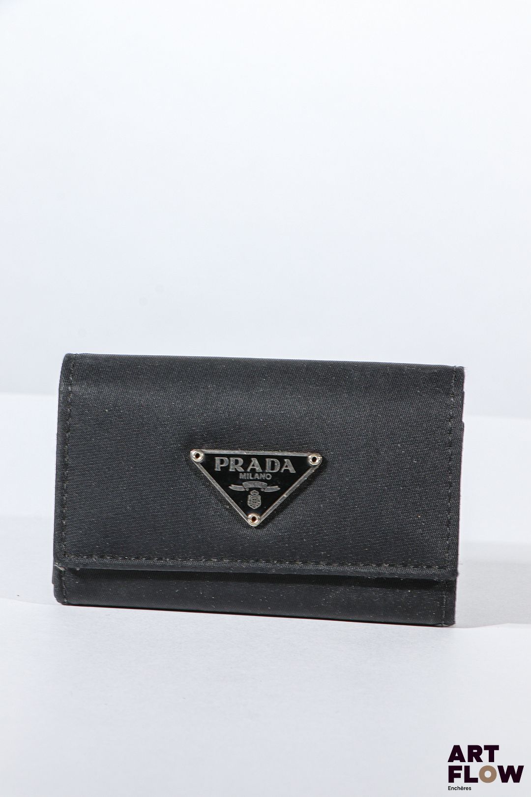PRADA Porte clés en tissu noir, bijouterie en métal argenté, fermeture à pression sous rabat. Dimensions : 6 x 10 cm Bon état général