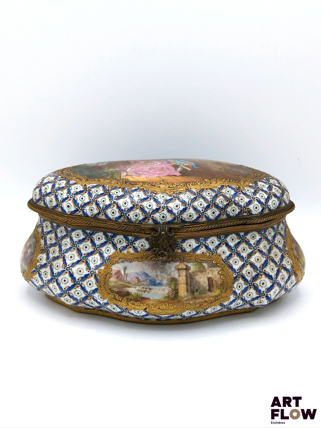 Dans le goût de SÈVRES Boîte en porcelaine ornée sur son couvercle d'une scène galante, et sur ses côtés de scènes lacustres dans le goût du XVIIIe siècle. Marque apocryphe au double L, lettre-date B. H. 9 x L. 21,5 cm x P 14 cm