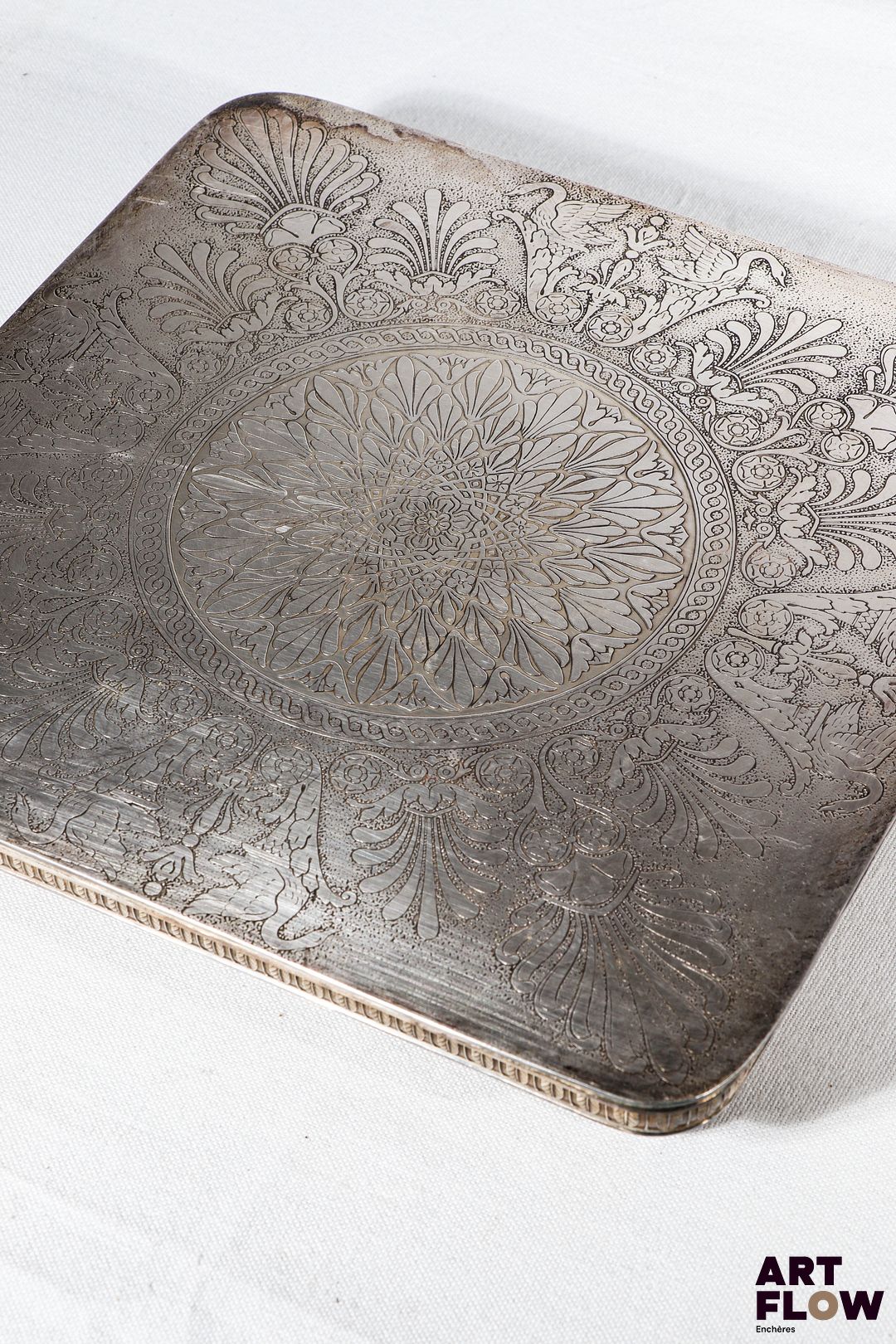 CHRISTOFLE Malmaison Dessous de plat carré en métal argenté à décor Empire ciselé de palmettes, cygnes et rinceaux. Reposant sur quatre pieds en gaine. Signé. Dans sa boîte d'origine. 22,5 x 22,5 cm Bon état général malgré quelques légers défauts (rayures d'usage).