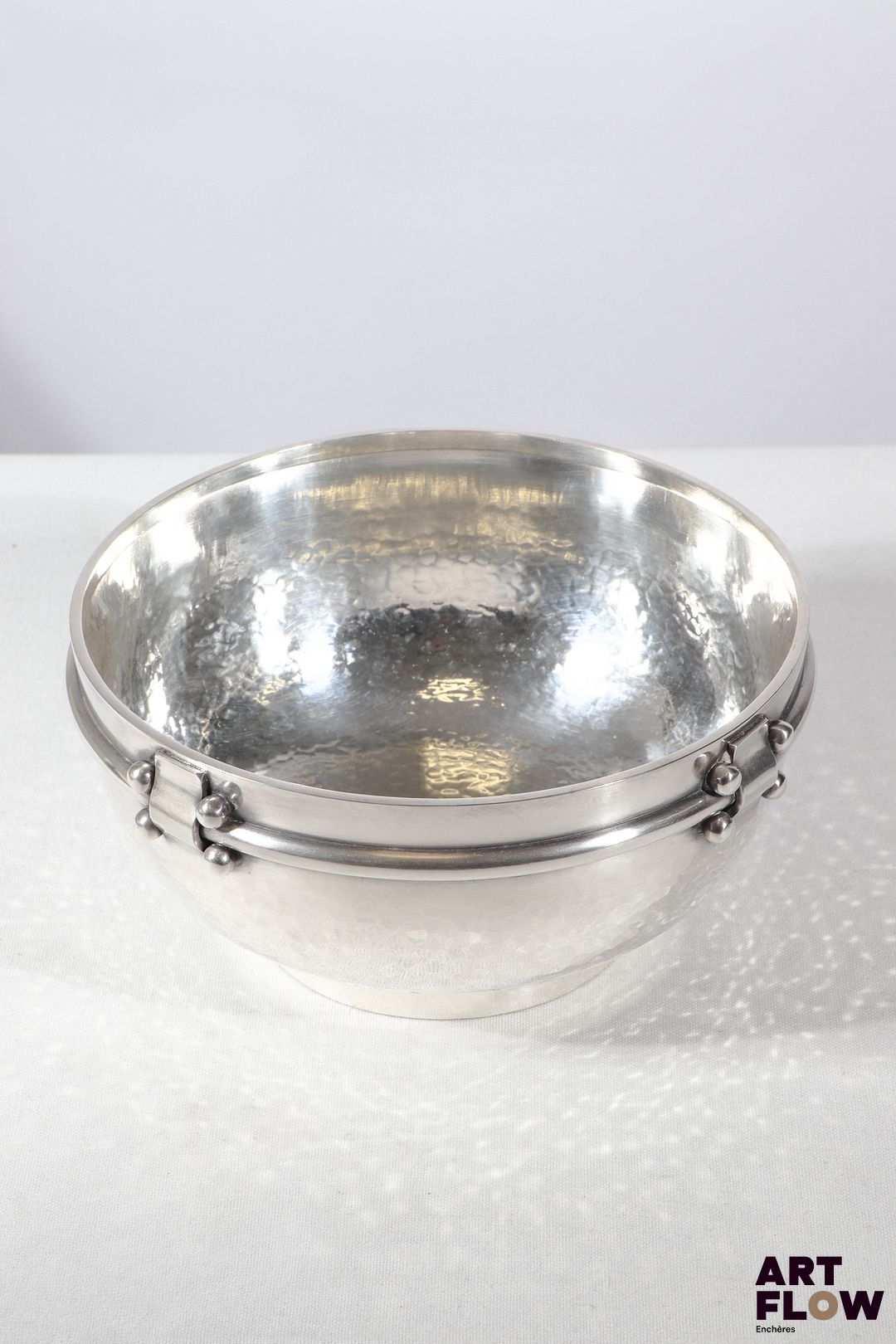Jean DESPRES (1889-1980) Soupière ou grand bol sur talon en métal argenté partiellement martelé. Signé J. DESPRES à la pointe sous la base. Haut. : 9,5 cm Diam. : 19,5 cm Dans sa boite d'origine Rayures d'usage