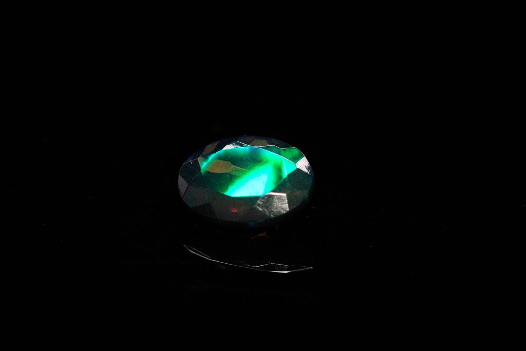 Opale facettée noire ovale. Beaux éclats de couleur, dominante verte. 1.84 ct. 11.0mm x 8.0mm