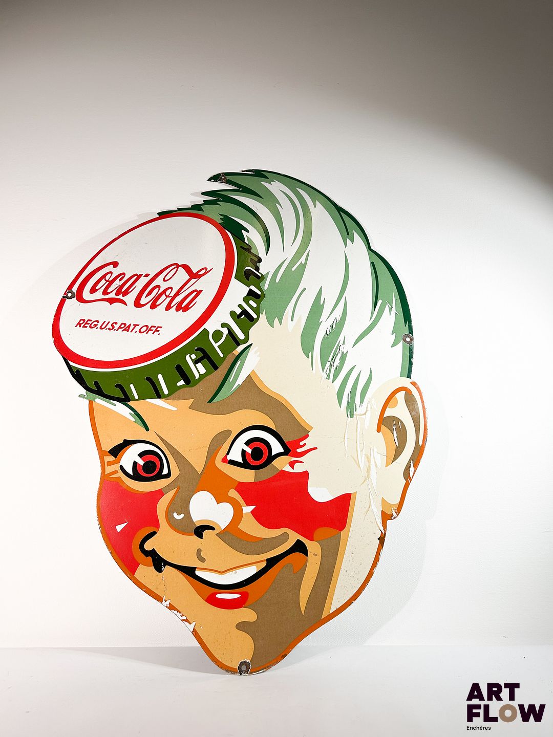 Grande plaque émaillée Coca-Cola à décor d'un visage Dimensions : 101 x 75 cm Petits éclats et traces de rouille