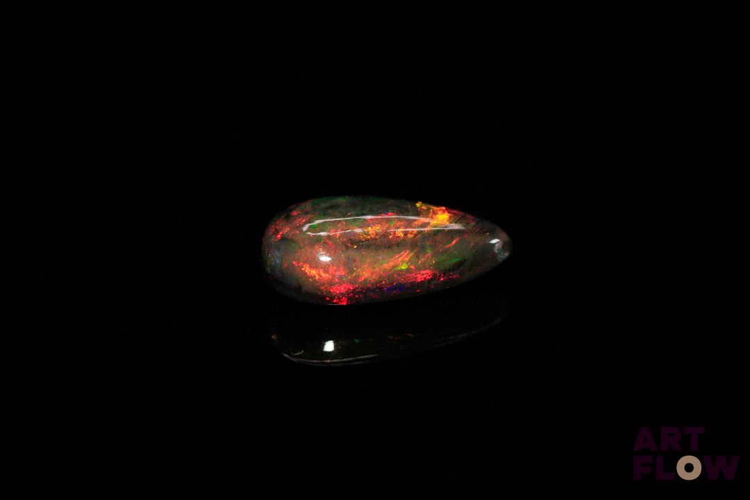 Opale noire cabochon poire. Beaux éclats de couleur, dominante rouge. 2.70 cts. 14.0mm x 7.5mm