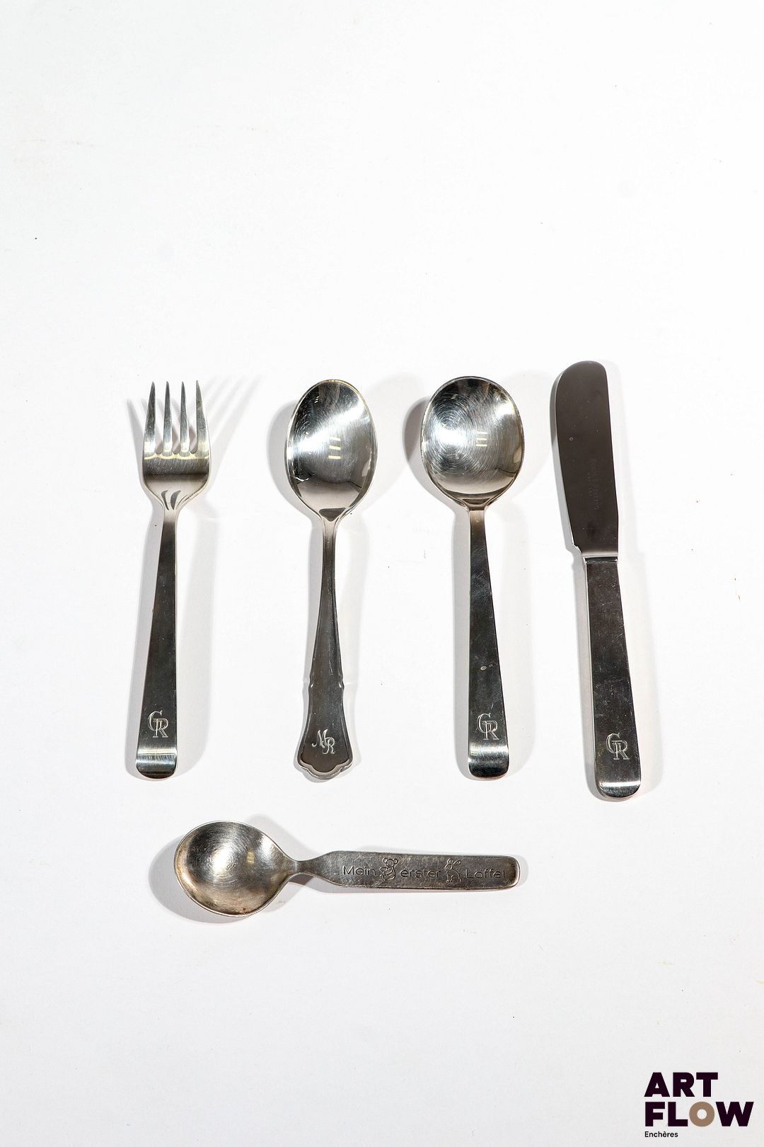 ROBBE & BERKING Ensemble de couverts en argent comprenant : - 1 cuillère, 1 fourchette et 1 couteau en argent 800/1000. Chiffrés GR - 1 cuillère en argent 925. Chiffré MR On y joint une petite cuillère Auerhahn en argent 800/1000 Poids : 200,07 g