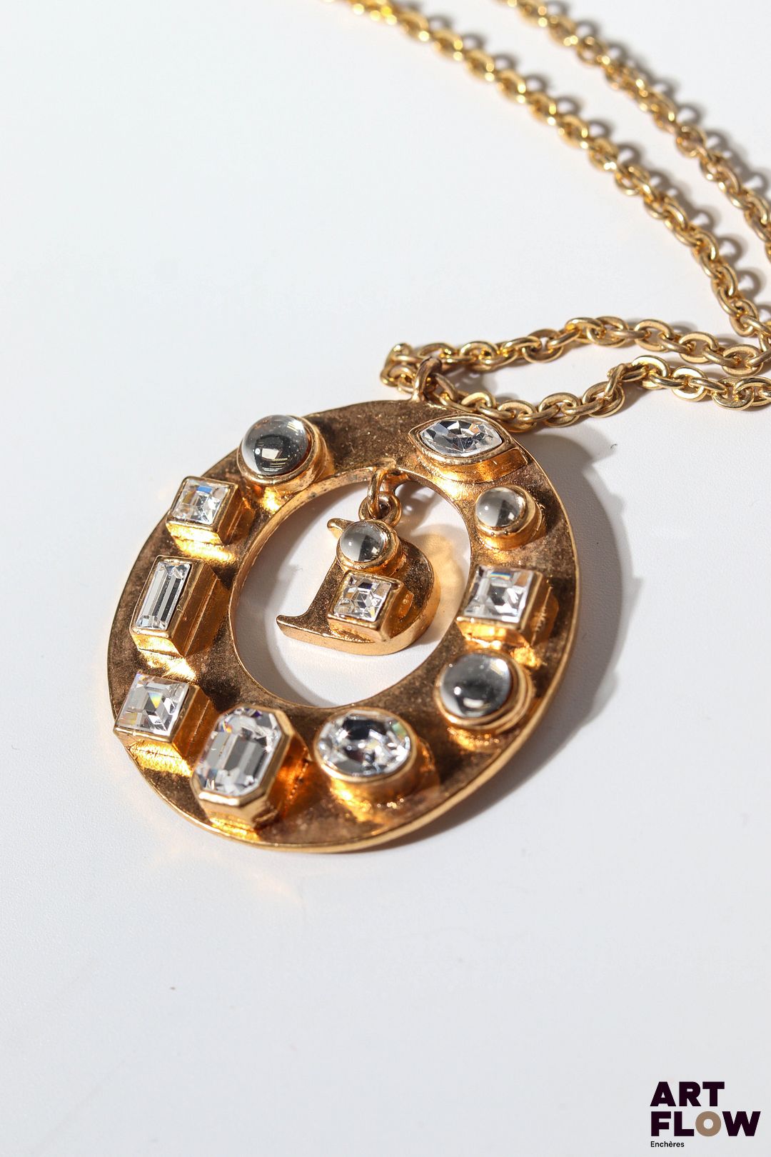 Christian DIOR boutique Sautoir en métal doré avec pendentif en forme de disque, orné d'imitations de diamants en serti clos et D de Dior en pampille. Longueur totale : 44 cm