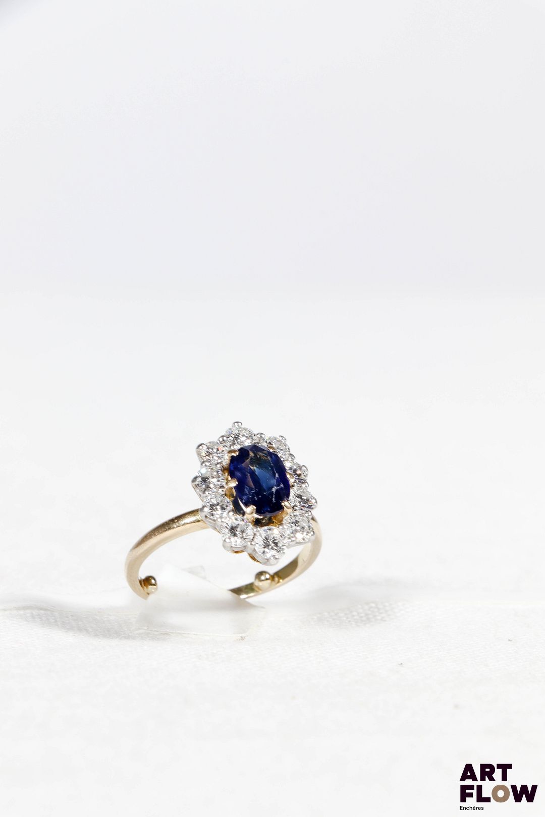 Bague en or jaune 750‰ et platine, de forme marguerite légèrement oblongue, composée au centre d’un saphir naturel d’un magnifique bleu soutenu, de forme ovale (8.7x6.2mm), pour un poids estimé de 1.80 carat, monté sur six griffes ; mis en valeur par un entourage de dix diamants taille brillant, sertis sur griffes, de qualité estimée G SI, pour un poids total de 1.36 carat environ. Très belle monture bicolore faite à la main de la deuxième moitié du XXe siècle. Présence de boules sur l’anneau pour éviter que la bague ne tourne une fois portée au doigt. (Très légères usures sur le saphir, un diamant légèrement égrisé) Diamants : 1.36 carat environ Saphir : 1.80 carat environ Poids : 5.55 g Tour de doigt : 52 avec les boules, convient pour un tour de doigt 54/55