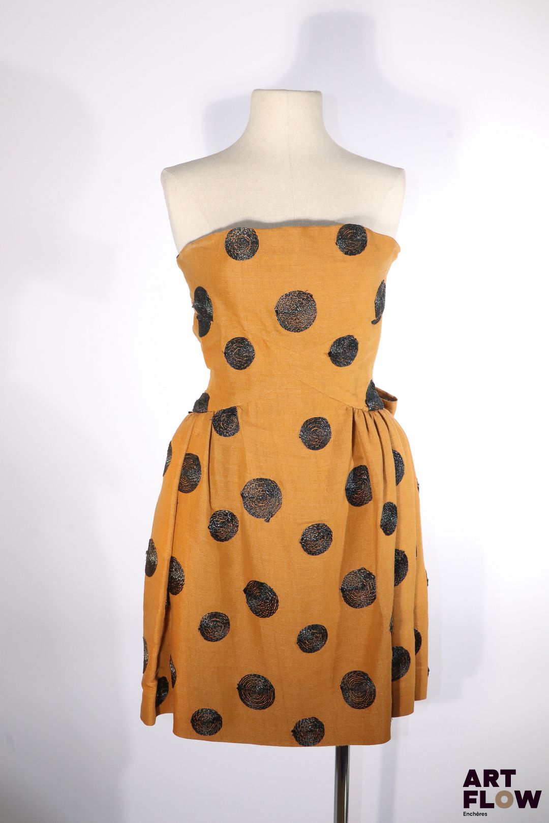 BALENCIAGA - Le Dix - Circa 1980 - Robe bustier en toile de coton et lin de camel rebrodée de cercles de raphia noir, plissée à la taille et rehaussée au dos de deux importants nœuds -Taille présumée 36 - Bon état général malgré quelques très légers défauts