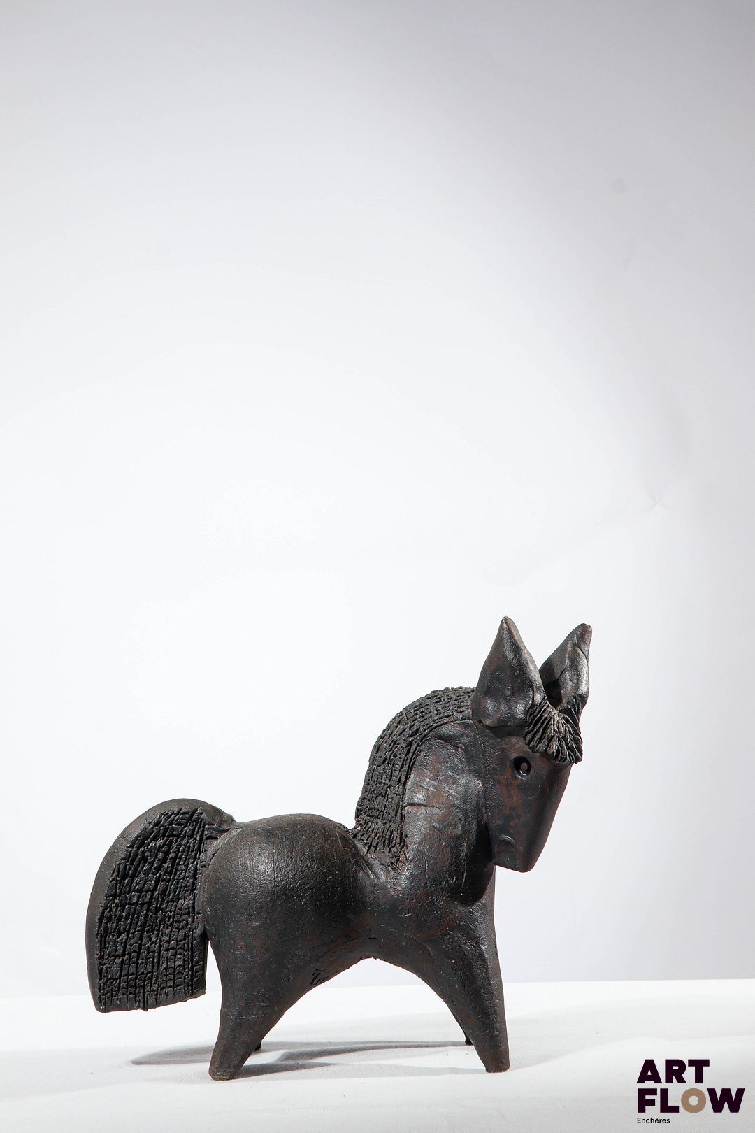 Dominique POUCHAIN (Né en 1956) Cheval Sculpture en céramique à couverte sombre patinée et partiellement incisée. Hauteur : 25,5 cm x Longueur : 32 cm x Largeur 13 cm environ. Un infime accident sous l'un des sabots.