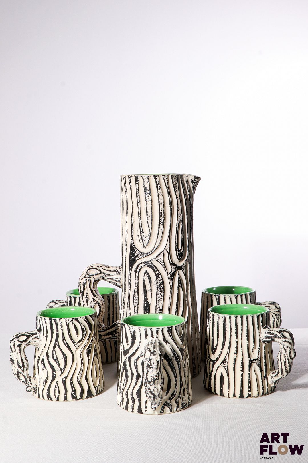 POL CHAMBOST (1906-1983) Service à orangeade 883 "Bois de bouleau" en faience émaillée à couverte polychrome, noire et blanche à l'extérieur et verte à l'intérieur, comprenant un pichet et 8 chopes. Pichet incisé "883, Pol Chambost, Made in France"et les chopes "Poterie Pol Chambost, 883, Made in France". H. pichet 27 cm H. chopes 10 cm Bibliographie : Philippe Chambost, "Pol Chambost, Sculpteur-Céramiste 1906-1983", Somogy Editions d'Art, Paris, 2006, modèle similaire p. 156