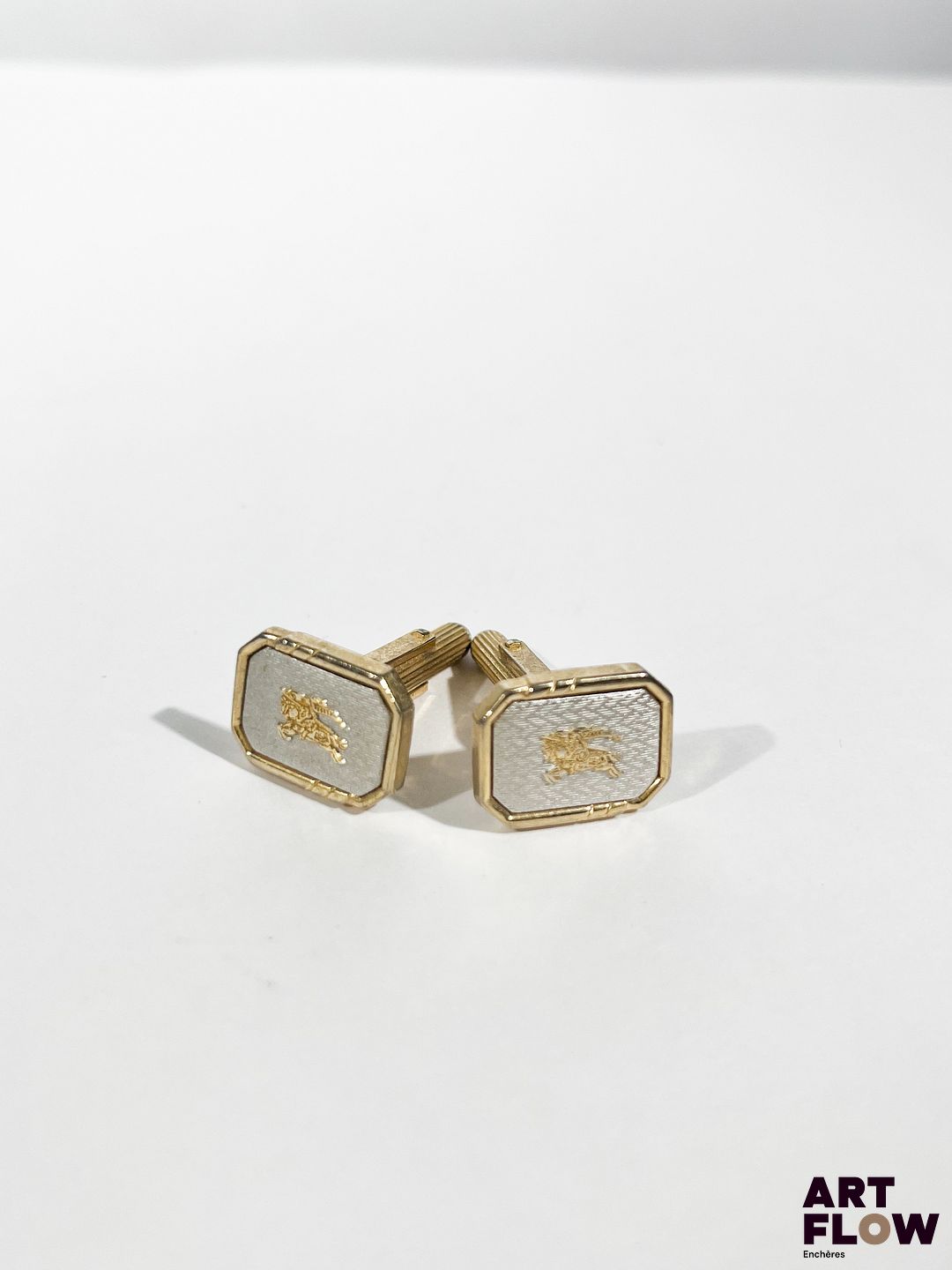 BURBERRY Paire de boutons de manchette en métal doré et argenté à décor guilloché centré du logo de la marque 1,5 x 1 cm env.
