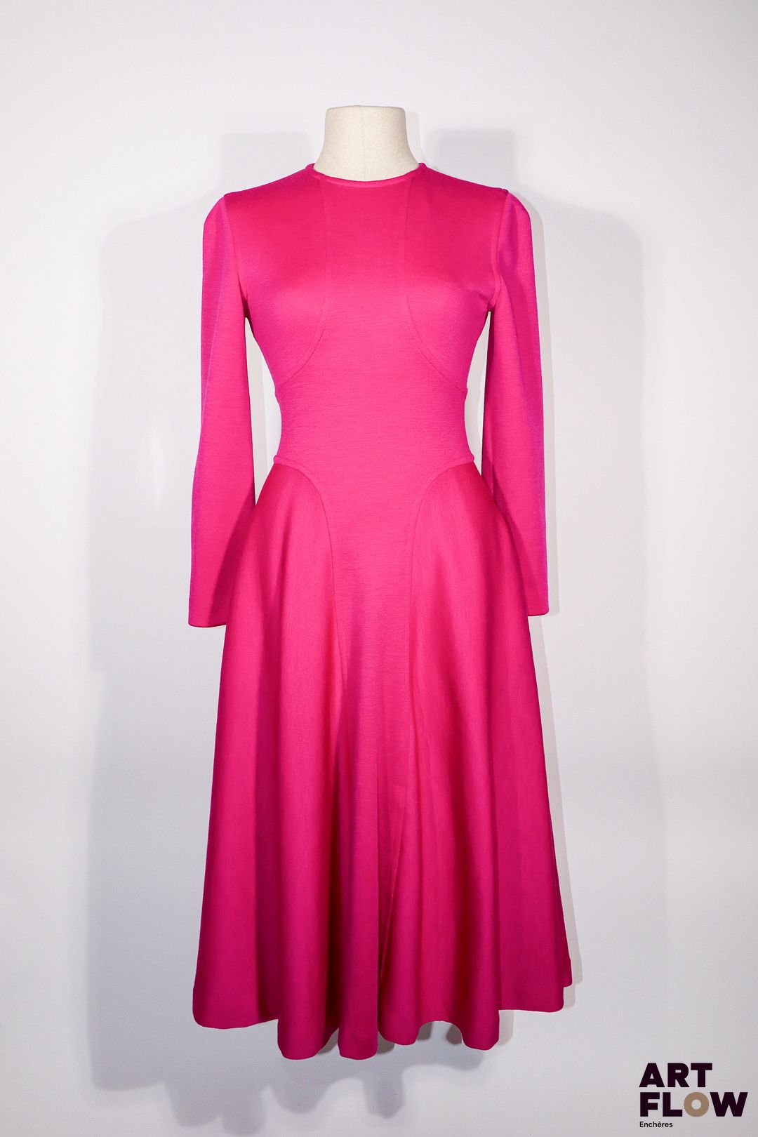 Attribué à BALENCIAGA - Ligne Dix - Circa 1980 - Robe longue en jersey de laine fuchsia à effet de découpe en longue croix donnant de l'ampleur à la jupe, et se nouant au dos par une boucle ovale ceinturant à volonté la taille, manches longues, deux poches verticales -Taille présumée 36/38 - Bon état général malgré quelques légers défauts