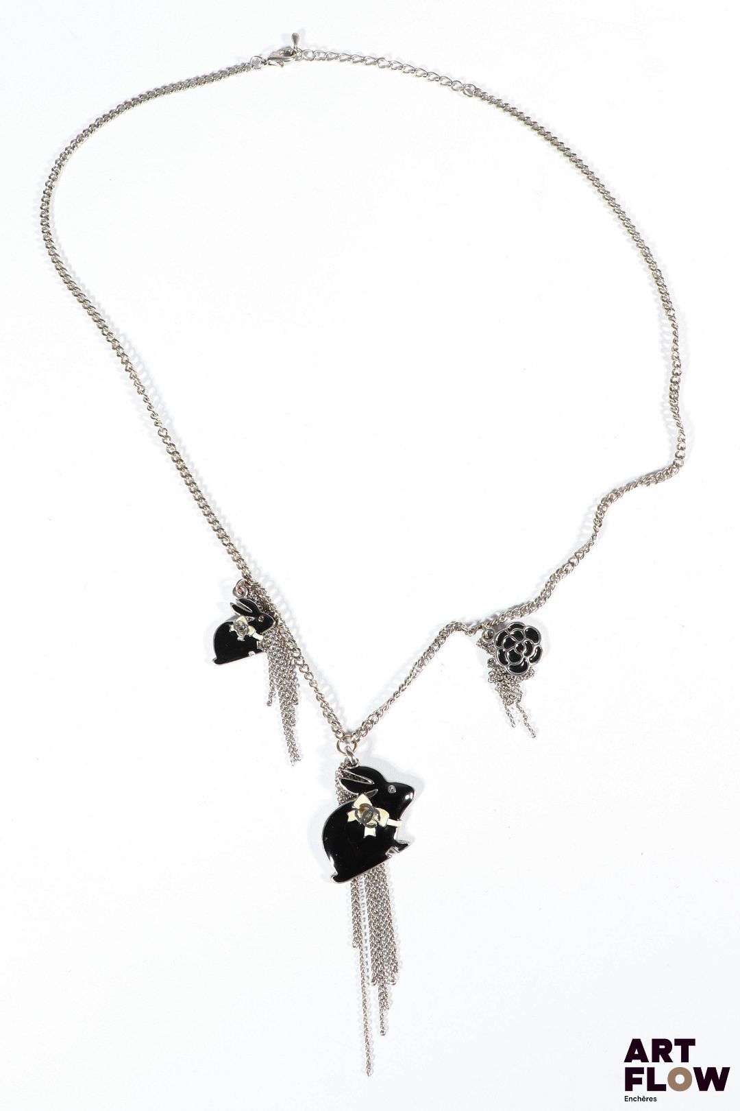 Attribué à CHANEL Collier en métal argenté orné de trois charm's à décor de lapins noirs et blancs et d'une fleur Monogramme Chanel présent sur les lapins Les décors de fleurs occupent une place essentielle dans l’univers joaillier de Chanel, inspirés par la nature chère à Gabrielle Chanel. Longueur : 62 cm