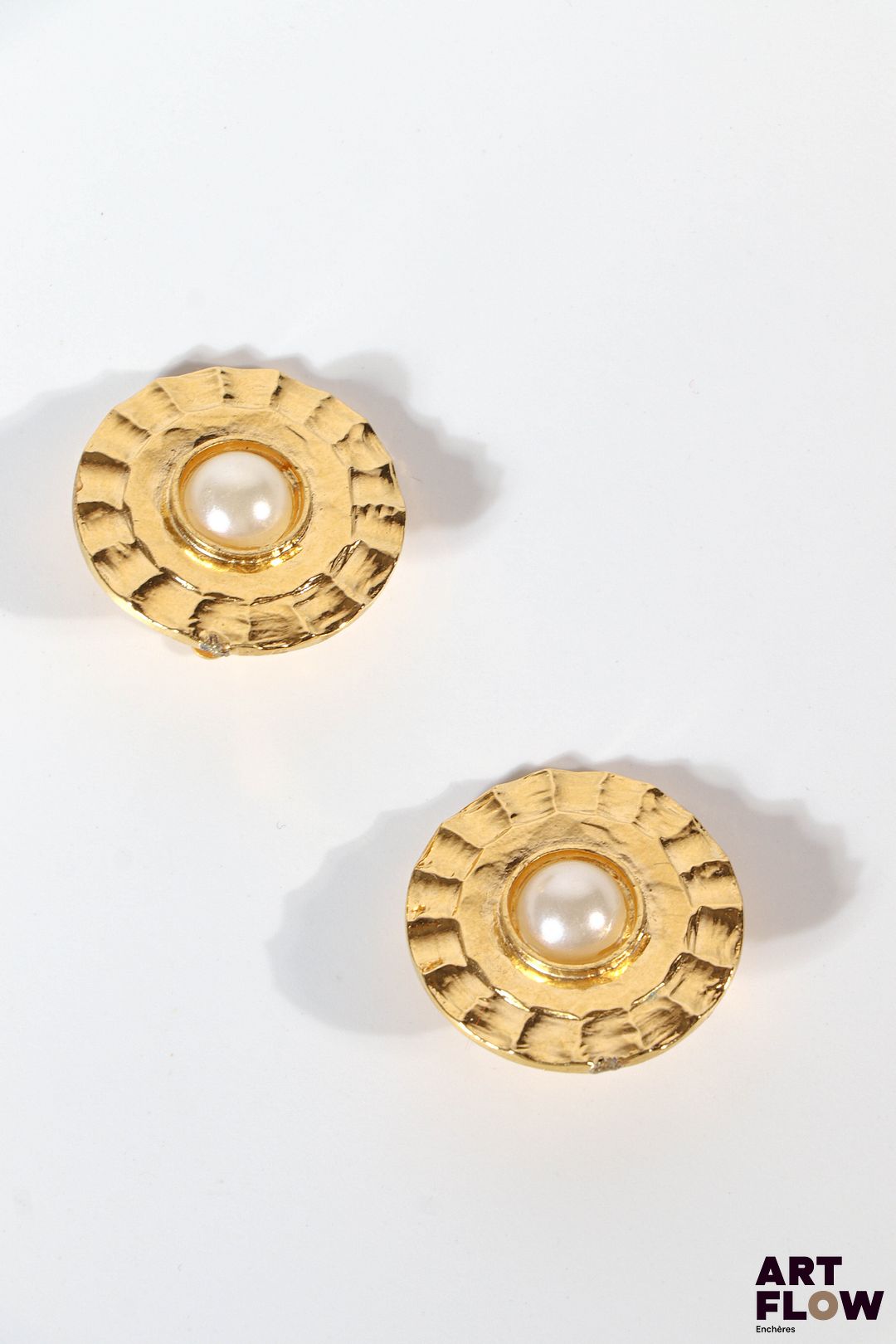 CHANEL Paire de clips d'oreille en métal doré orné au centre d'une perle synthétique Signés Diamètre : 3 cm