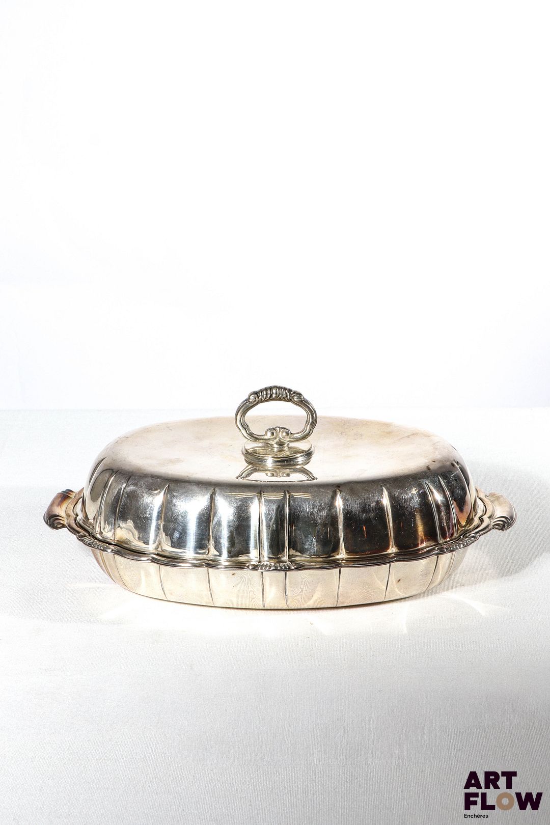 Ravier couvert en argent, de forme légèrement chantournée, les anses et le frétel à décor de volutes. De style Louis XV. Poids : 645,60 g Dimensions : H.10 x L. 26 cm environ