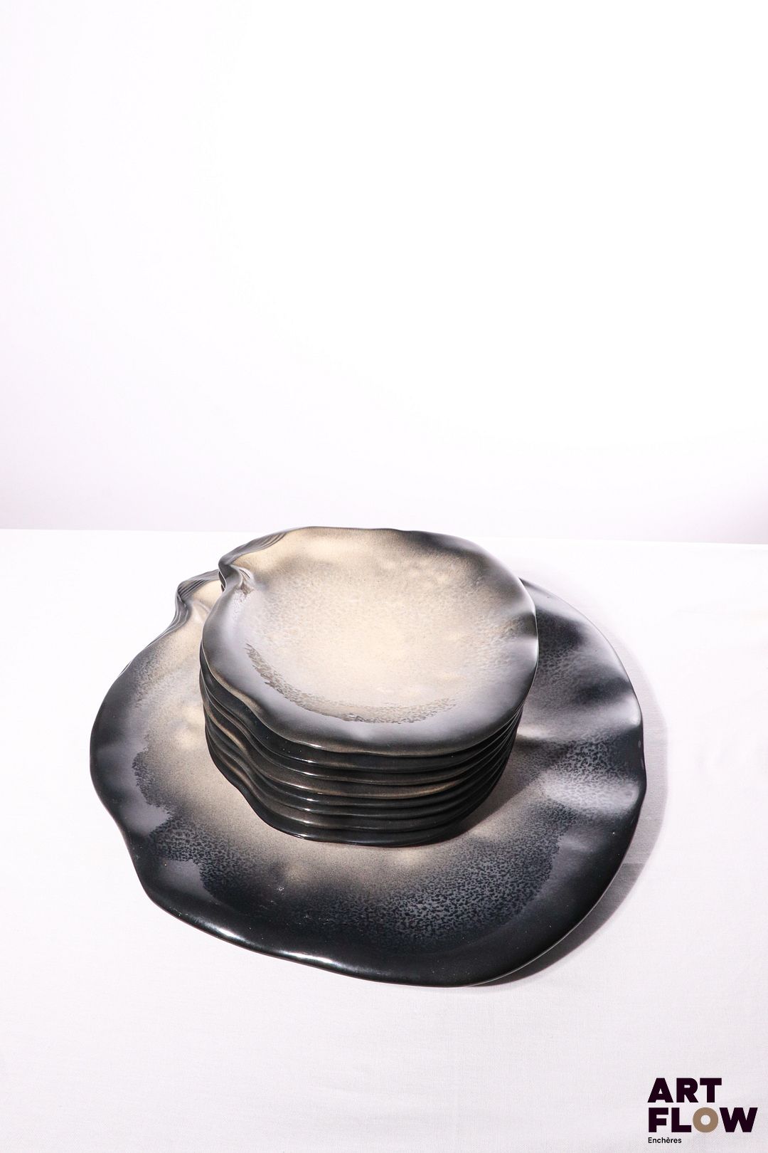 POL CHAMBOST (1906-1983) Service 1025 "Coquille" en faience émaillée à couverte polychrome dans les tons nacrés gris et bleus, comprenant un grand plat et 8 assiettes. . Assiettes incisées "1025, Poterie Pol Chambost, Made in France", le plat "1042, Poterie Chambost, France". Assiettes : 26 x 24,5 cm Plat : 45 x 42 cm Bibliographie : Philippe Chambost, "Pol Chambost, Sculpteur-Céramiste 1906-1983", Somogy Editions d'Art, Paris, 2006, modèle similaire p. 26 ; p. 95