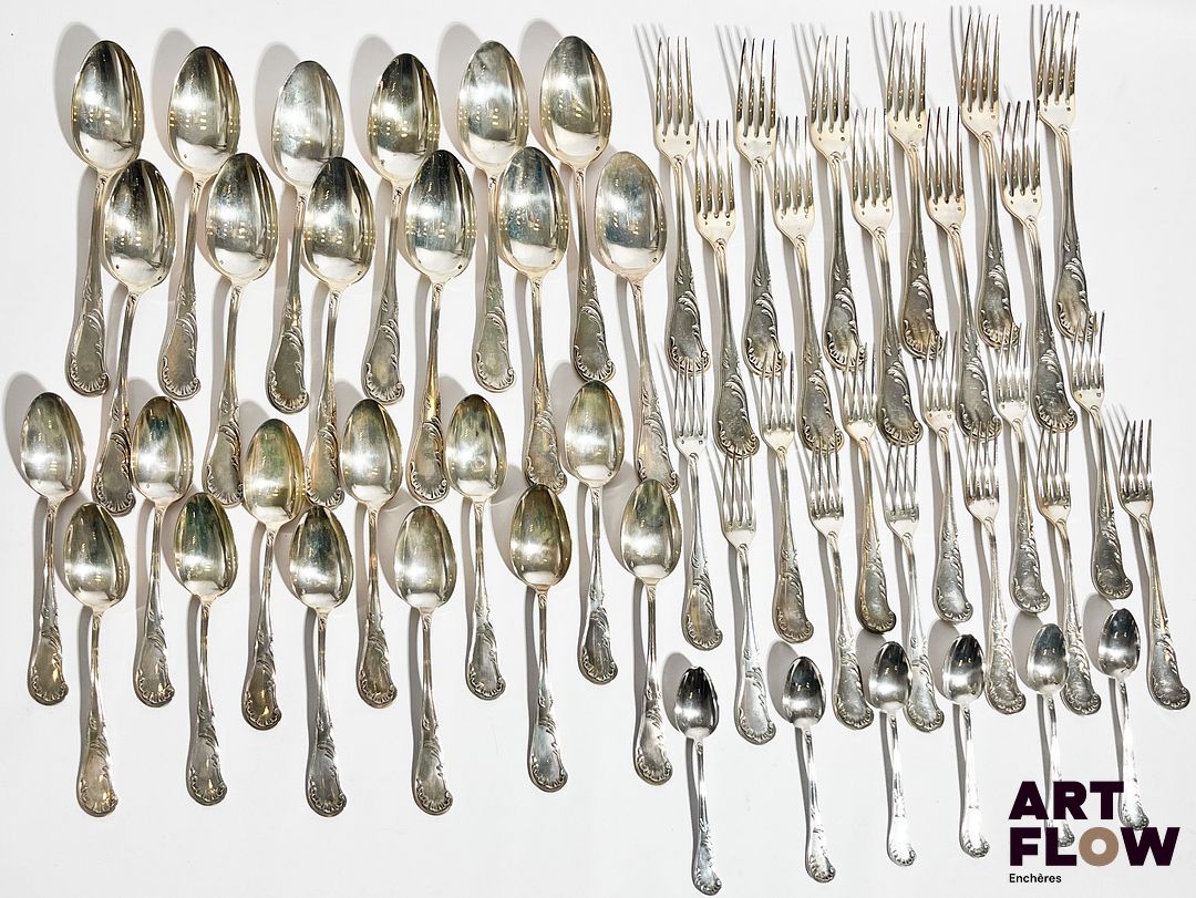 Henri SOUFFLOT (actif entre 1884 et 1910) Ménagère en argent de style rocaille, à décor de rinceaux et feuilles d'acanthe comprenant : 11 fourchettes, 12 cuillères, 12 couverts à entremet (12 fourchettes et 12 cuillères) 6 petites cuillères On y joint 12 couteaux à entremet et 11 couteaux (+1 d'un modèle différent) en argent fourré, de style similaire, le manche monogrammé, lame inox. Poids brut : 3226 g pour les fourchettes et cuillères uniquement 3364 gr avec couteaux