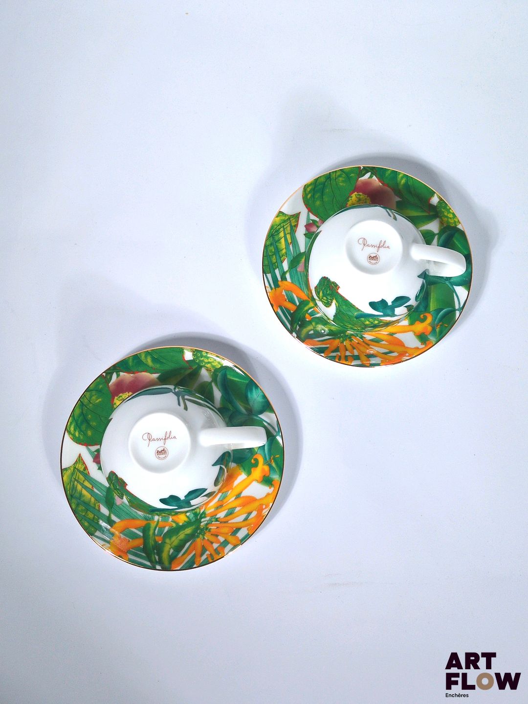 HERMÈS Modèle Passifolia Ensemble comprenant 2 tasses et leur sous tasse en porcelaine à décors imprimés et filet de couleur or sur le pourtour. Dessiné par Nathalie Rolland-Huckel. Diamètre : 15 cm pour la sous tasse