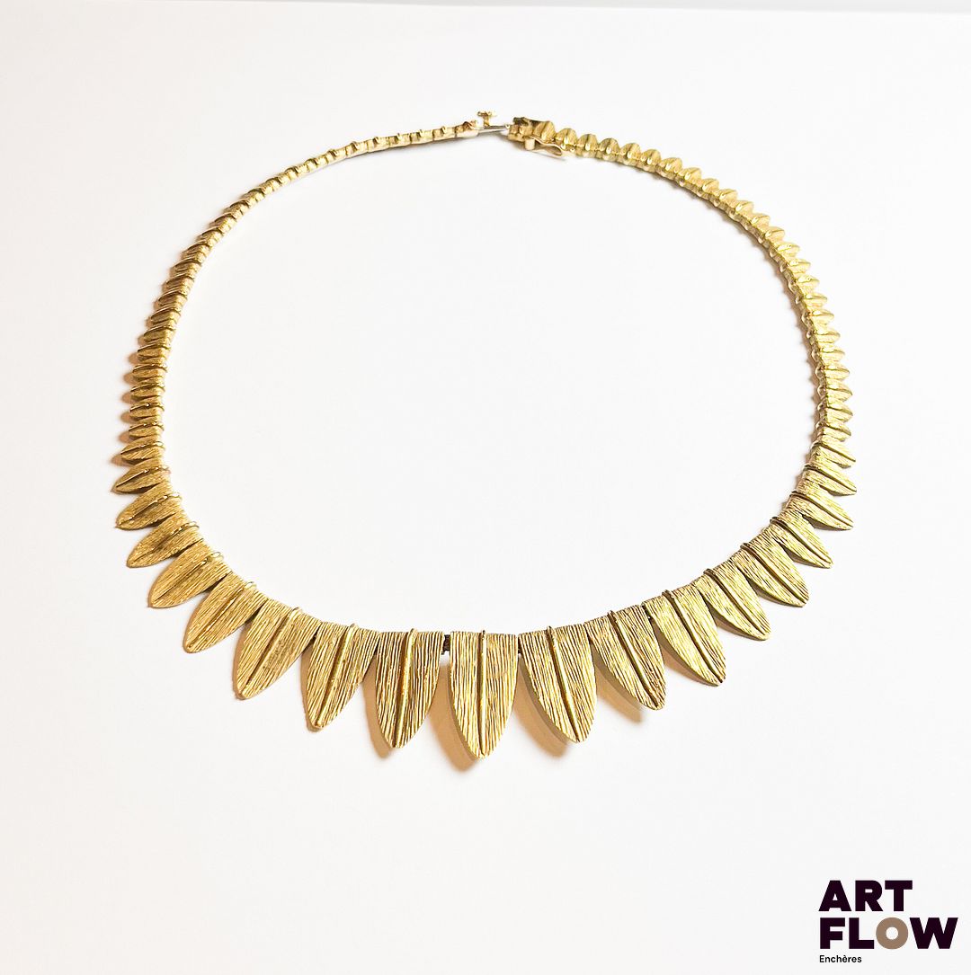 Collier en or jaune 750‰, poinçon tête de rhinocéros, entièrement composé de feuilles stylisées en chute ; fermoir cliquet et huit de sécurité. Travail Français de la 2 ème moitié du XXe siècle Poids : 34.76 g Longueur : 36 cm – largeur max : 1.8 cm Expertise : Philippine Vanheems