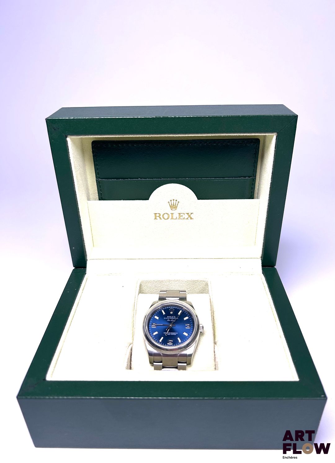 ROLEX Montre bracelet homme en acier, modèle Oyster Perpetual Air King, à mouvement mécanique à remontage automatique, le boîtier de forme ronde à cadran à fond soleillé bleu, index 3-6-9 et bâtons luminescents, lunette lisse, seconde centrale, le bracelet Oyster brossé. Années 2009 Diamètre 34mm Référence 114200 Bon état général Fourni avec un set important comprenant boîte, carte de garantie, tags d'origine, protection de lunette Fonctionnelle au moment de la rédaction du catalogue, mécanisme non garanti. C’est en 1958 que la Rolex Air-King rejoint officiellement la grande famille Rolex, affichant fièrement son nom en italique sur le cadran, une typographie unique dans la marque. Choisie par Hans Wilsdorf lui-même, cette signature distinctive est restée inchangée au fil des décennies, renforçant son identité singulière. Expert : Alexis Francis-Boeuf - AFB Horlogerie