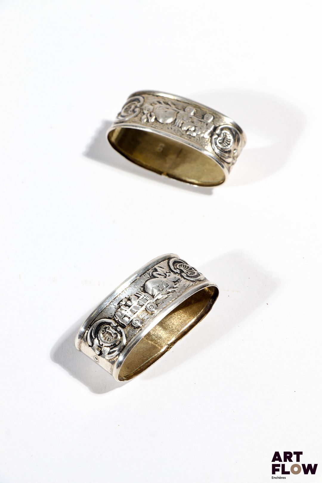 Ensemble de 2 ronds de serviette en argent à décor de lapin et coquille et cartouche gravé "Olivier" sur l'un et "M. Helene" sur l'autre. Largueur : 4 cm Poids : 5,39 g pour l'un et 6,22 g pour l'autre