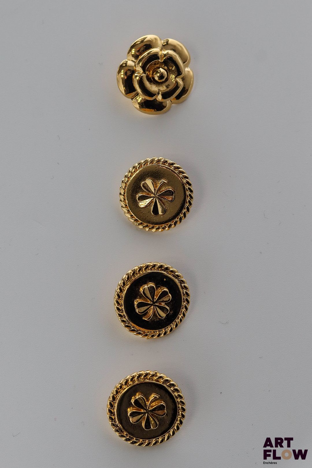 CHANEL Lot de 3 boutons à décor de trèfle. On y joint un bouton en forme de camélia.