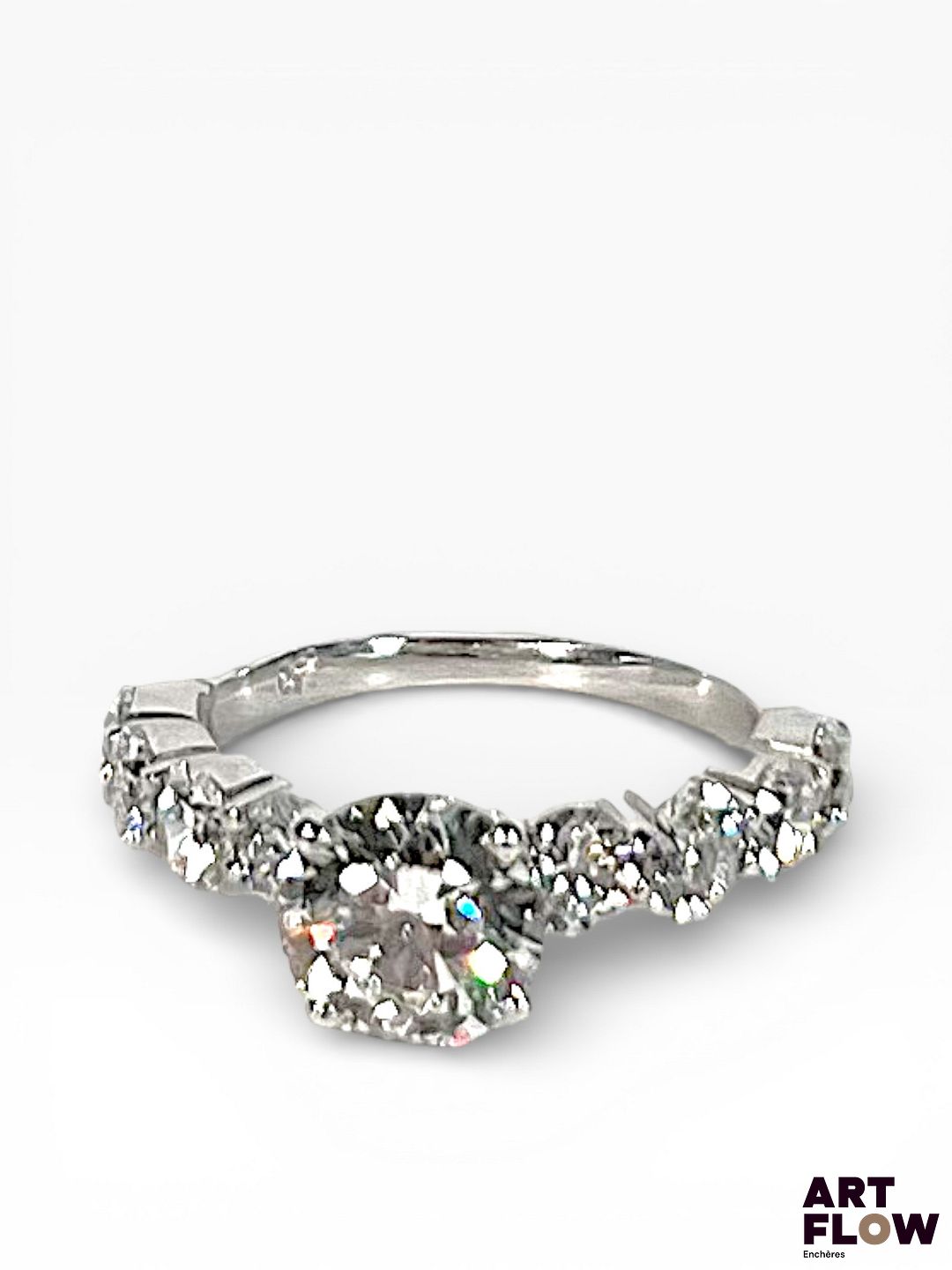 Bague en or blanc 18 carats, centré d'un diamant de synthèse de 1,52 carats, entourée de diamants de synthèse faisant approximativement 0.1 carats chacun Poids : 3,9g TDD : 52 Avec son certificat