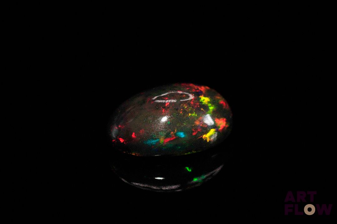 Opale noire cabochon ovale. Beaux éclats de couleur, dominante rouge, dominante verte. 7.54 cts. 17.0mm x 13.0mm