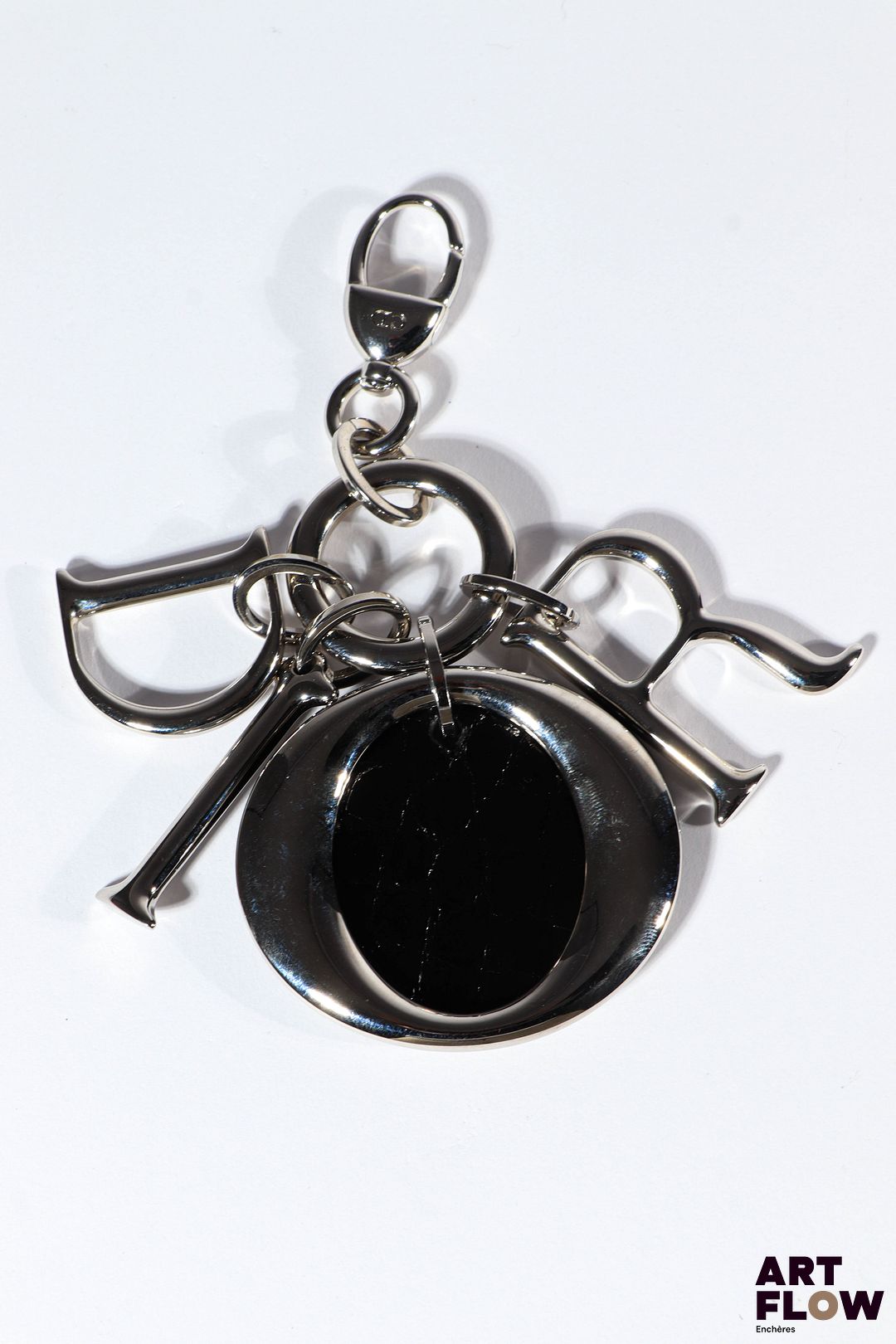 CHRISTIAN DIOR Porte-clé avec charms en métal argenté et pièce en cuir vernie noir. Signé
