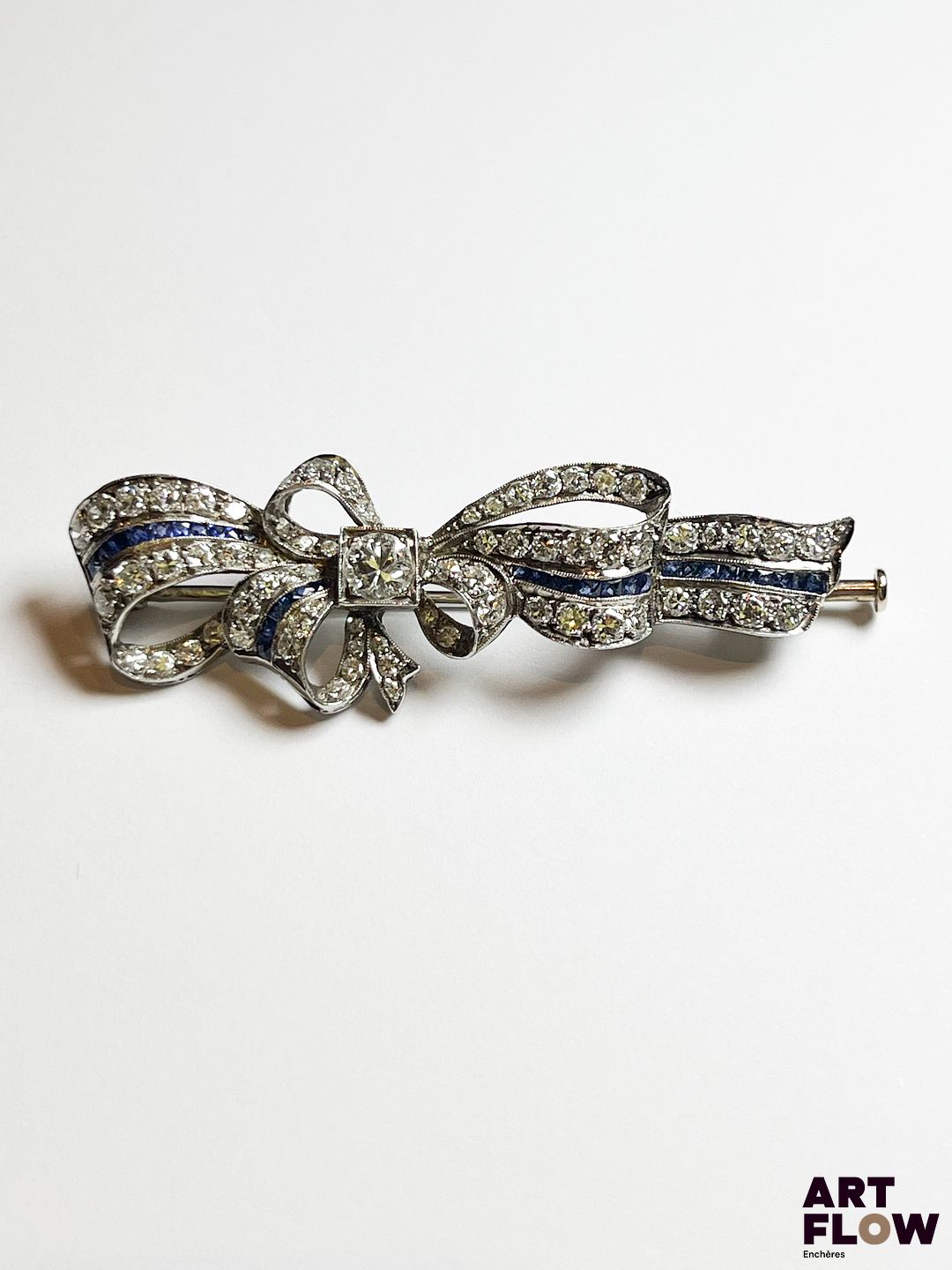 Broche noeud en or blanc 750/°°, diamants et fine ligne de saphirs Poids brut : 9,69gr