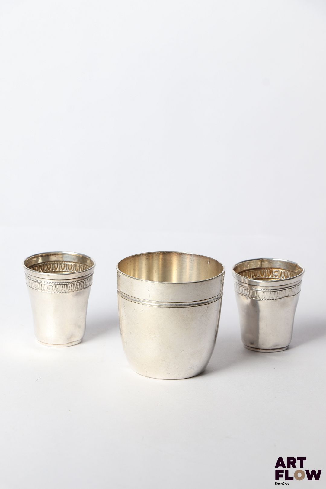 Paire de gobelets à liqueur en argent (Minerve), à décor de frises de plantes d'eau. Poids : 18,41 gr Accidents (enfoncements) On y joint une tombale en métal argenté.