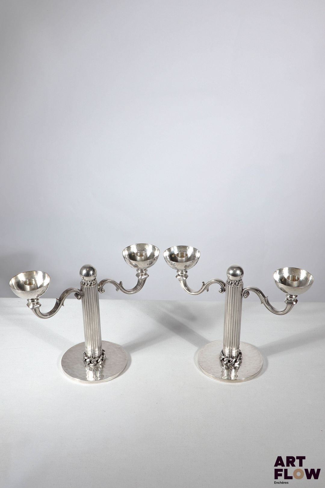 Jean DESPRES (1889-1980) Paire de chandeliers à 2 lumières en métal argenté, à décor de chaines et fut cannelé. Signé J. DESPRES à la pointe sous la base. Haut. : 20 cm L. : 26,5 cm Rayures d'usage