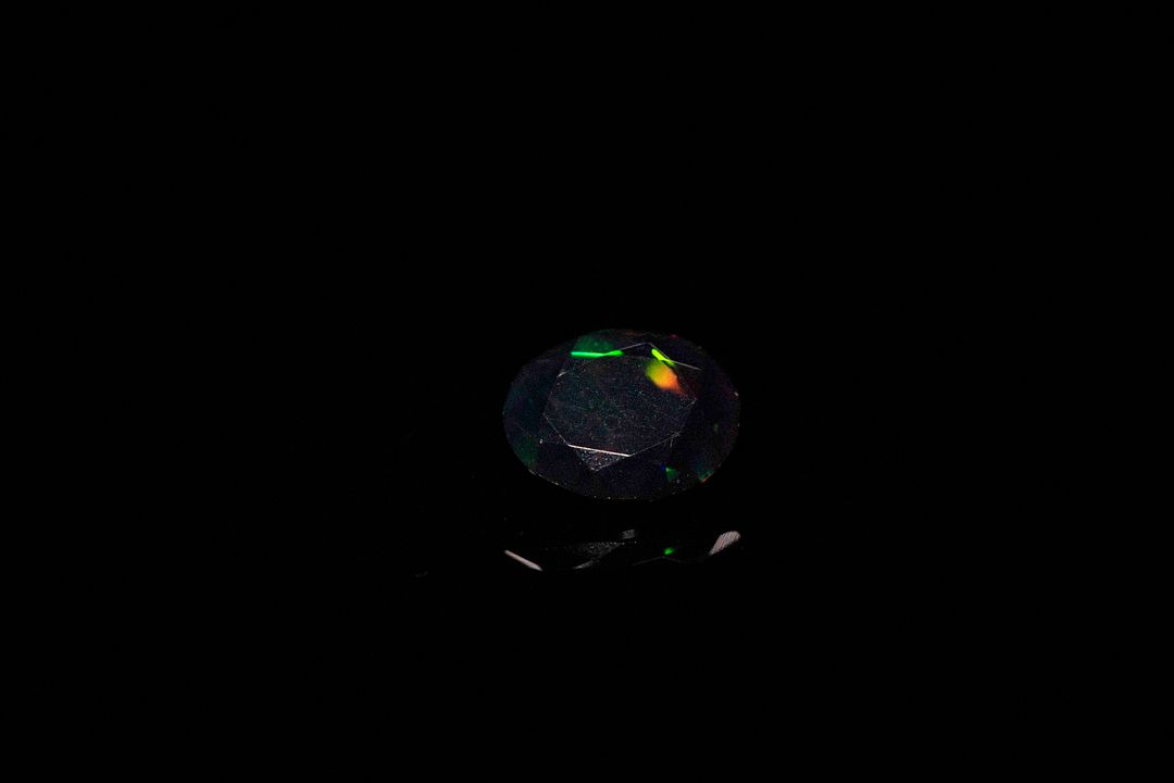 Opale facettée noire ovale. Beaux éclats de couleur. 0.83 ct. 8.8mm x 7.0mm