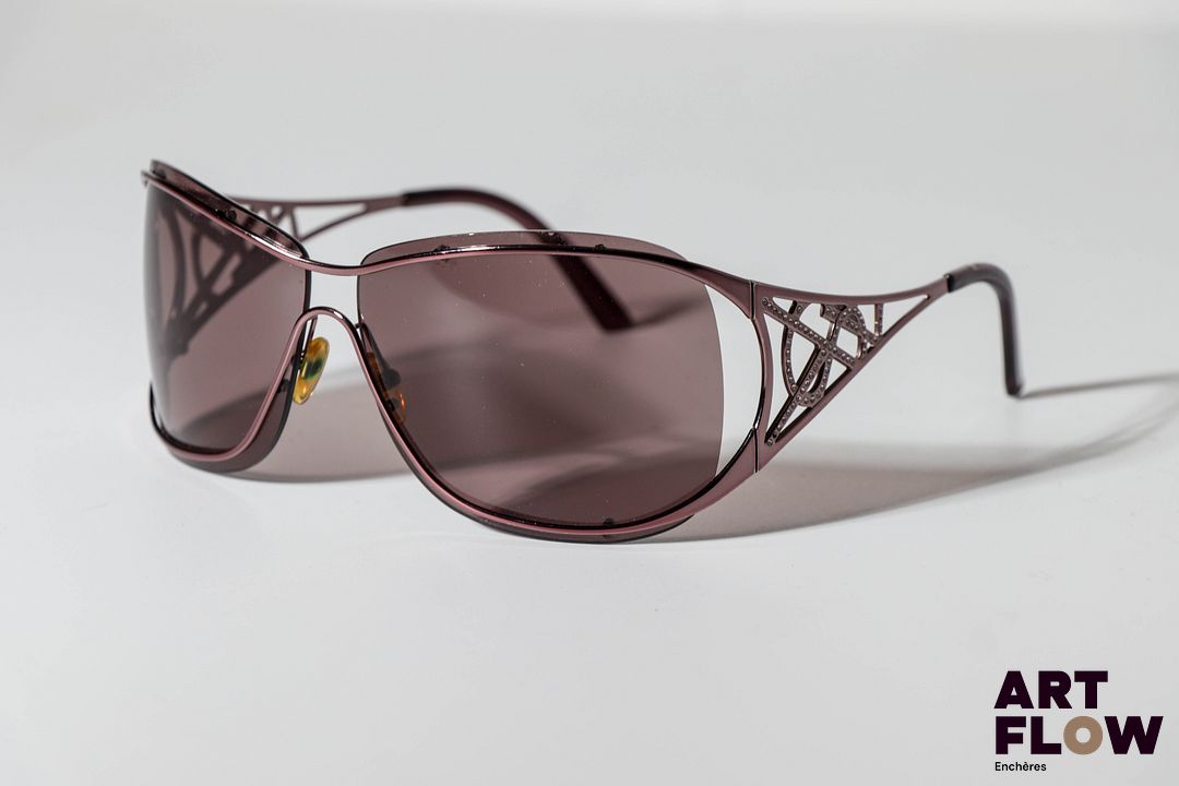 YSL Paire de lunettes de soleil, les branches ornées du logo a strass. Quelques petites rayures. Dans un étui Dolce & Gabbana.