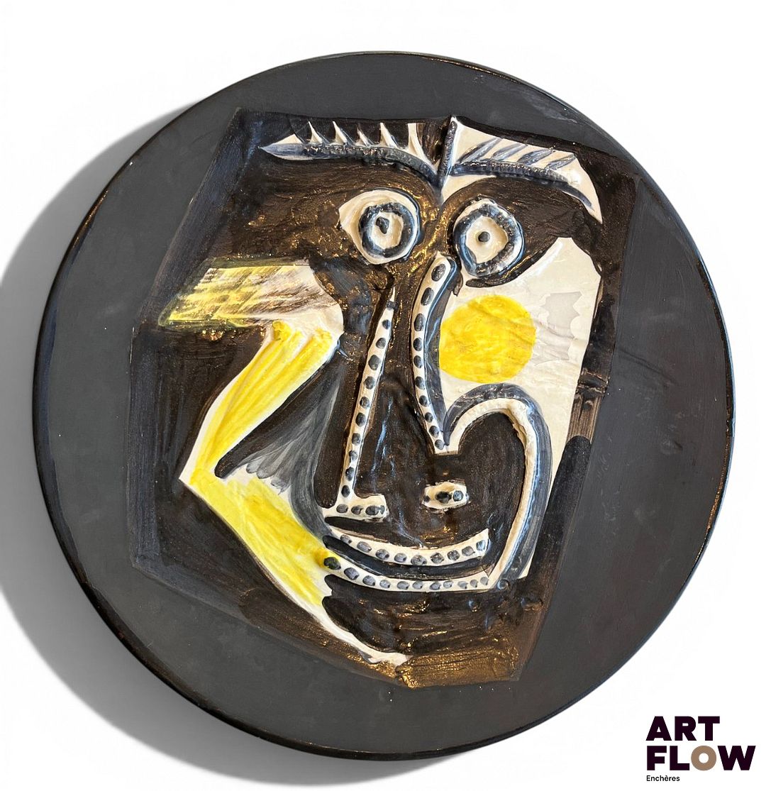 Pablo PICASSO (1881-1973) & ATELIERS MADOURA – VALLAURIS (céramiste) Plat rond « Visage », modèle créé en 1960. Empreinte originale en terre de faïence blanche, décor aux engobes sous couverte partielle au pinceau ; ivoire, jaune, bleu, brun, noir mat. Tiré à 100 exemplaires (petits éclats en bordure et sous le talon et défaut de matière en façade). Signé du cachet Empreinte originale Picasso, Madoura plein feu et justifié au noir 96/100. Diam. 42 cm Bibliographie : Alain Ramié, Picasso, catalogue de l’œuvre céramique édité 1947-1971, éditions Madoura, Vallauris, 1988, modèle référencé sous le n°446 et reproduit p. 234. Expert : Cabinet Marcilhac