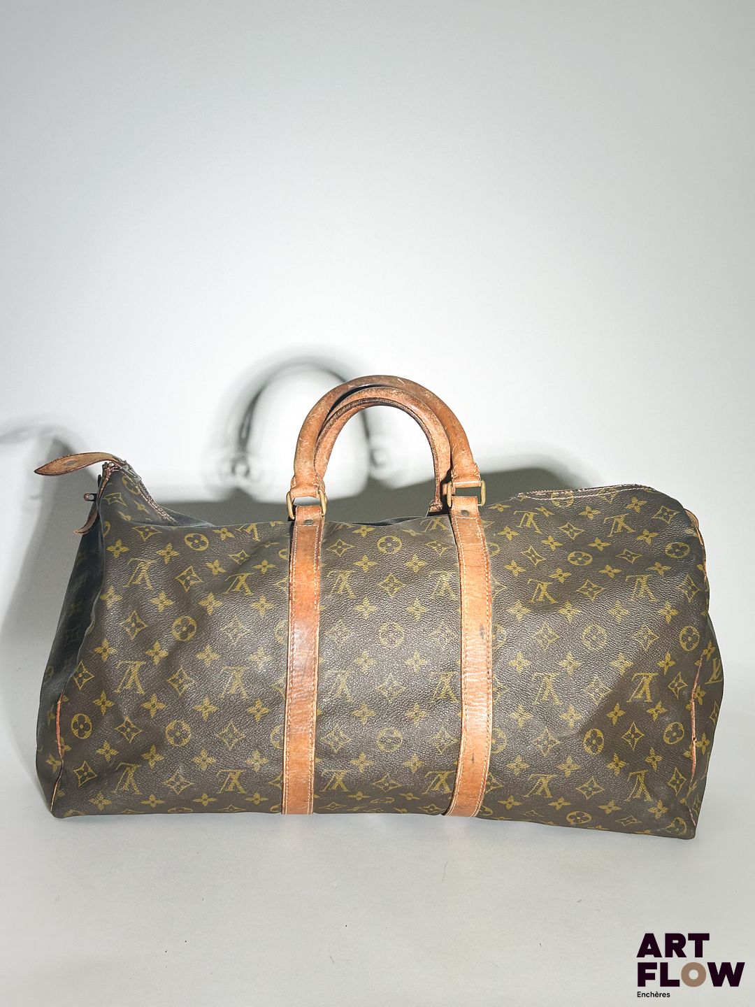 LOUIS VUITTON Modèle Keepall Sac de voyage en toile enduite monogrammée et cuir naturel Dimensions : 25 x 50 x 25 cm Usures : déchirures au zip, taches, traces (voir photos)