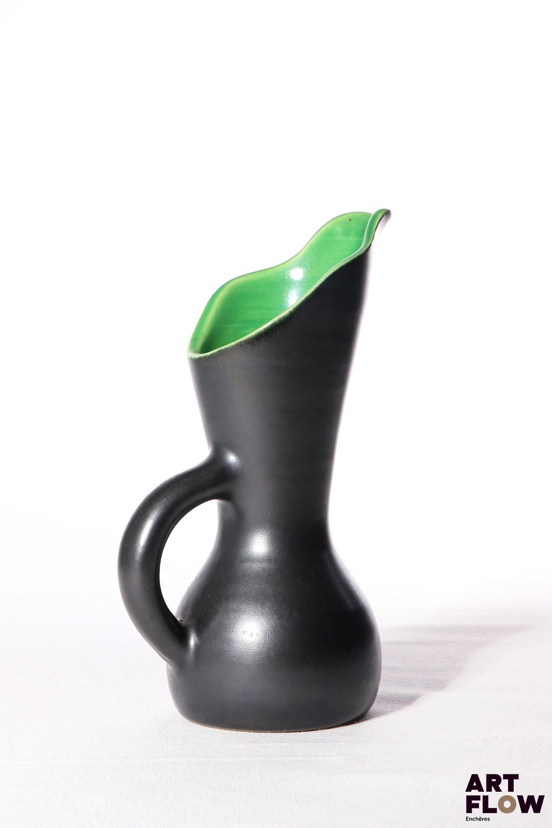 POL CHAMBOST (1906-1983) Pichet 898 en faience émaillée à couverte noire à l'extérieure, verte à l'intérieur. Incisé au revers "Poterie Pol Chambost" et tampon "Made in France" 20 x 10 cm env. Bibliographie : Philippe Chambost, "Pol Chambost, Sculpteur-Céramiste 1906-1983", Somogy Editions d'Art, Paris, 2006, modèle similaire p. 72