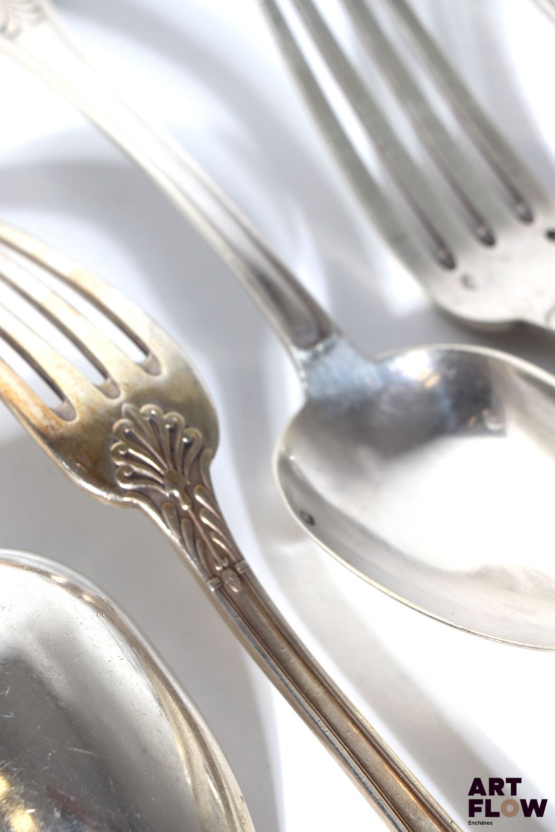 Lot de 12 couverts en argent (12 fourchettes et 13 cuillères), à décor de rinceaux stylisés. Monogrammés. Poids : 1936,51 grammes