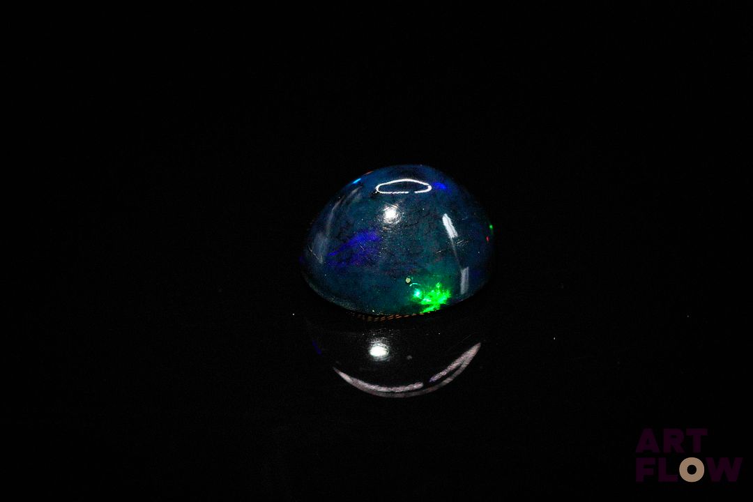 Opale noire cabochon ovale. Beaux éclats de couleur, dominante bleue. 2.86 cts. 11.0mm x 9.0mm