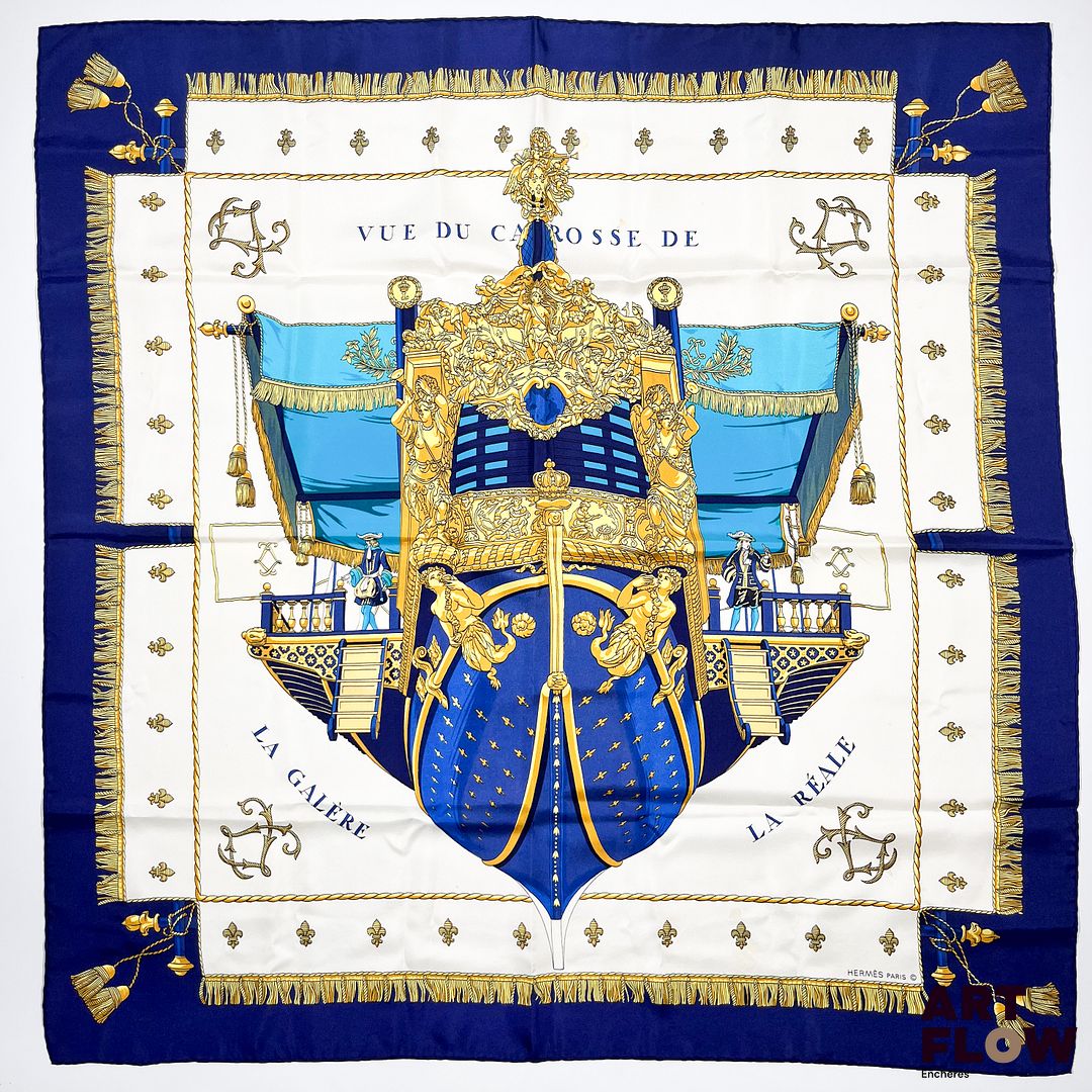 HERMÈS Modèle "La Réale". Carré en twill de soie à bordure bleue marine. 90 × 90 cm. Bon état général malgré quelques légers défauts.