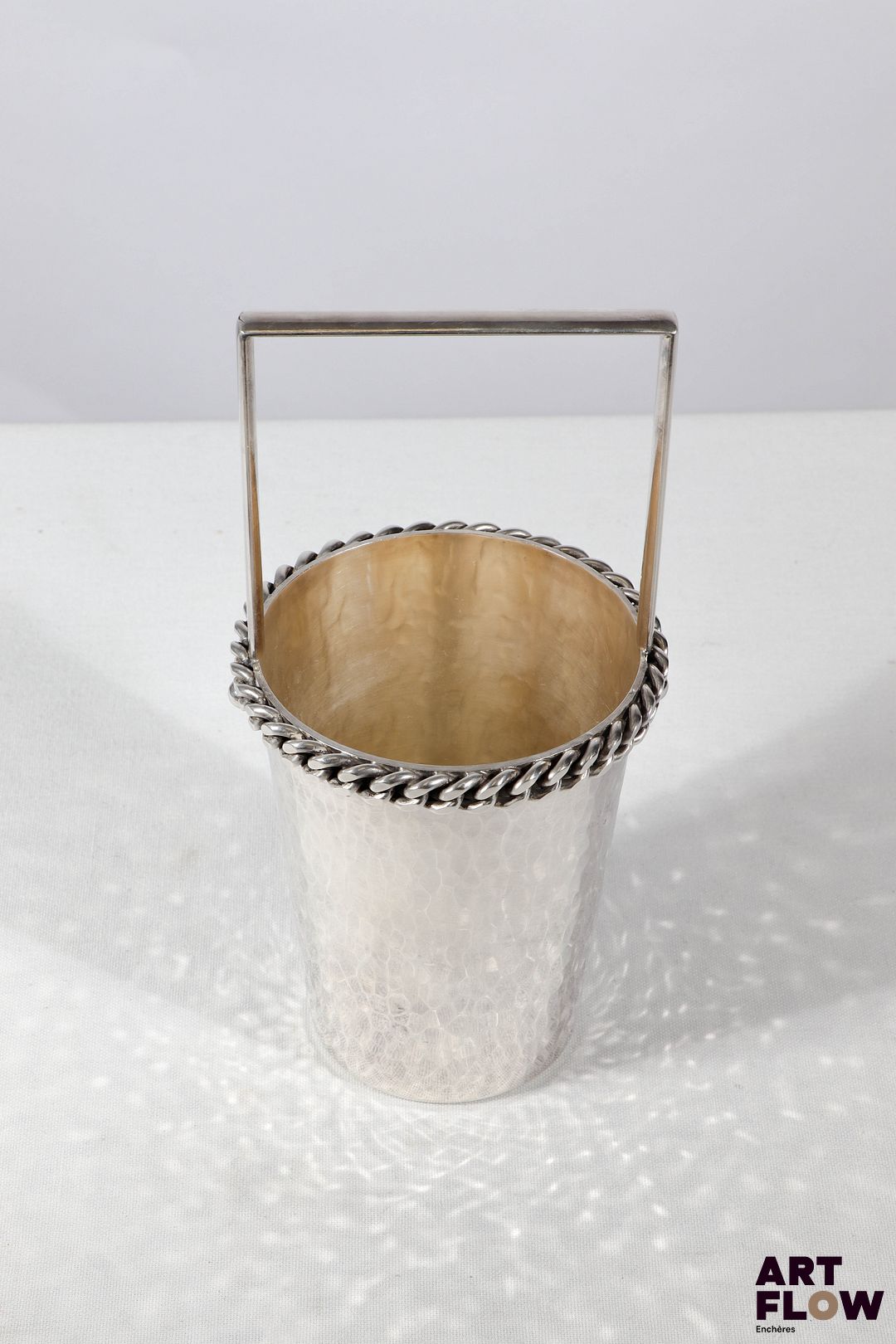 Jean DESPRES (1889-1980) Seau à glace en métal argenté martelé, le col souligné d'une chaine. Signé J. DESPRES à la pointe sous la base. Haut. : 21,5 cm Diam. : 10 cm Dans sa boite d'origine Rayures d'usage