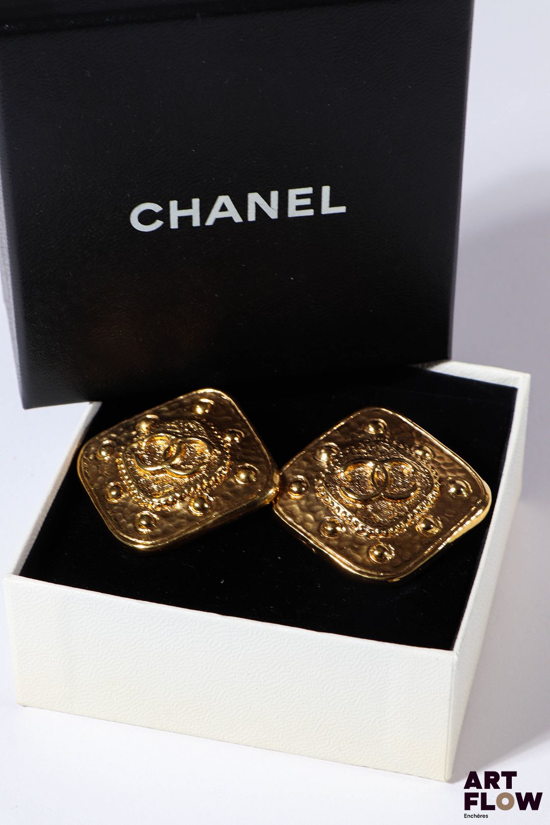 CHANEL Paire de clips d'oreilles en métal doré de forme carrée. Dims : 3 x 3 cm environ Dans leur boîte d'origine.