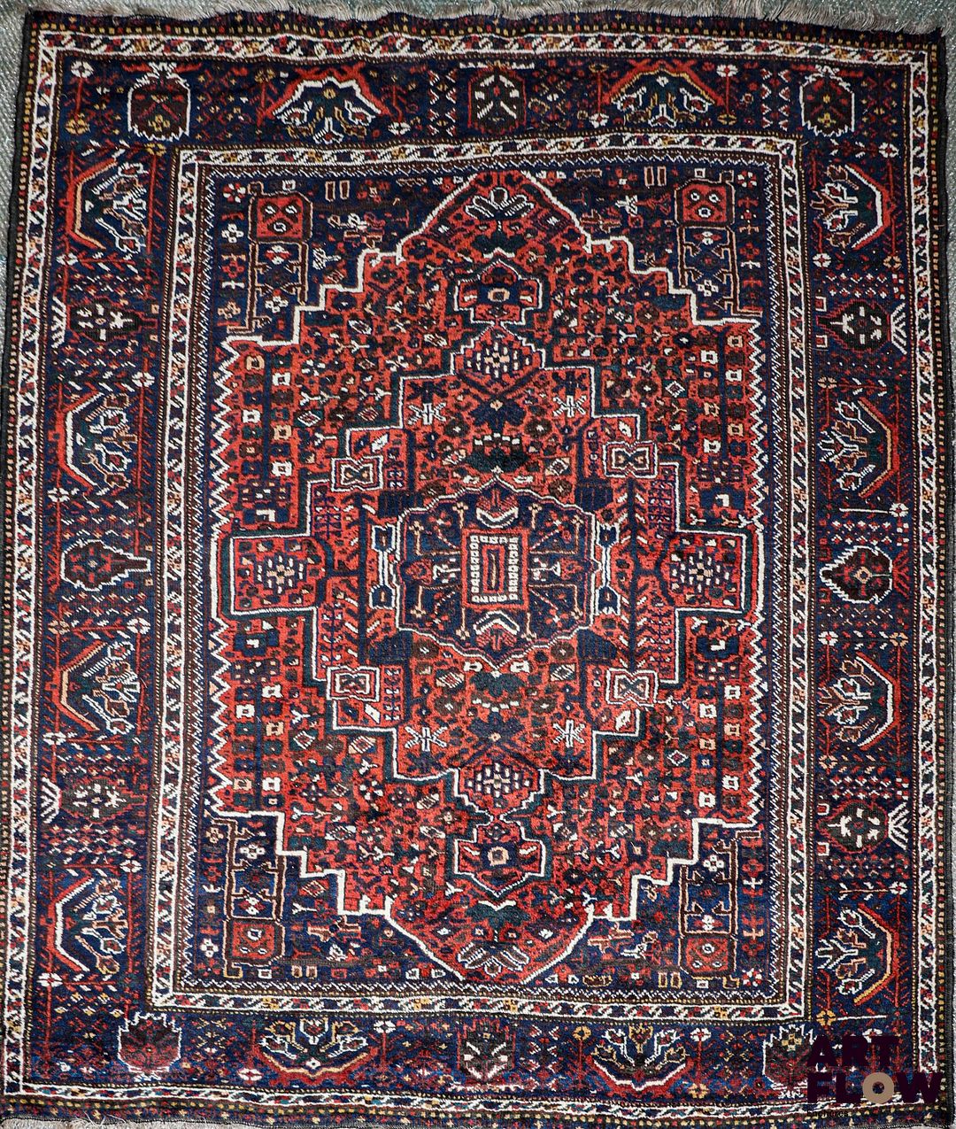IRAN - SHIRAZ Tapis en laine à décor dans les tons rouges d'un losange central H. 210 x L. 176 cm (hors franges) Bon état général malgré quelques légers défauts (poussières, petites usures d'usage)